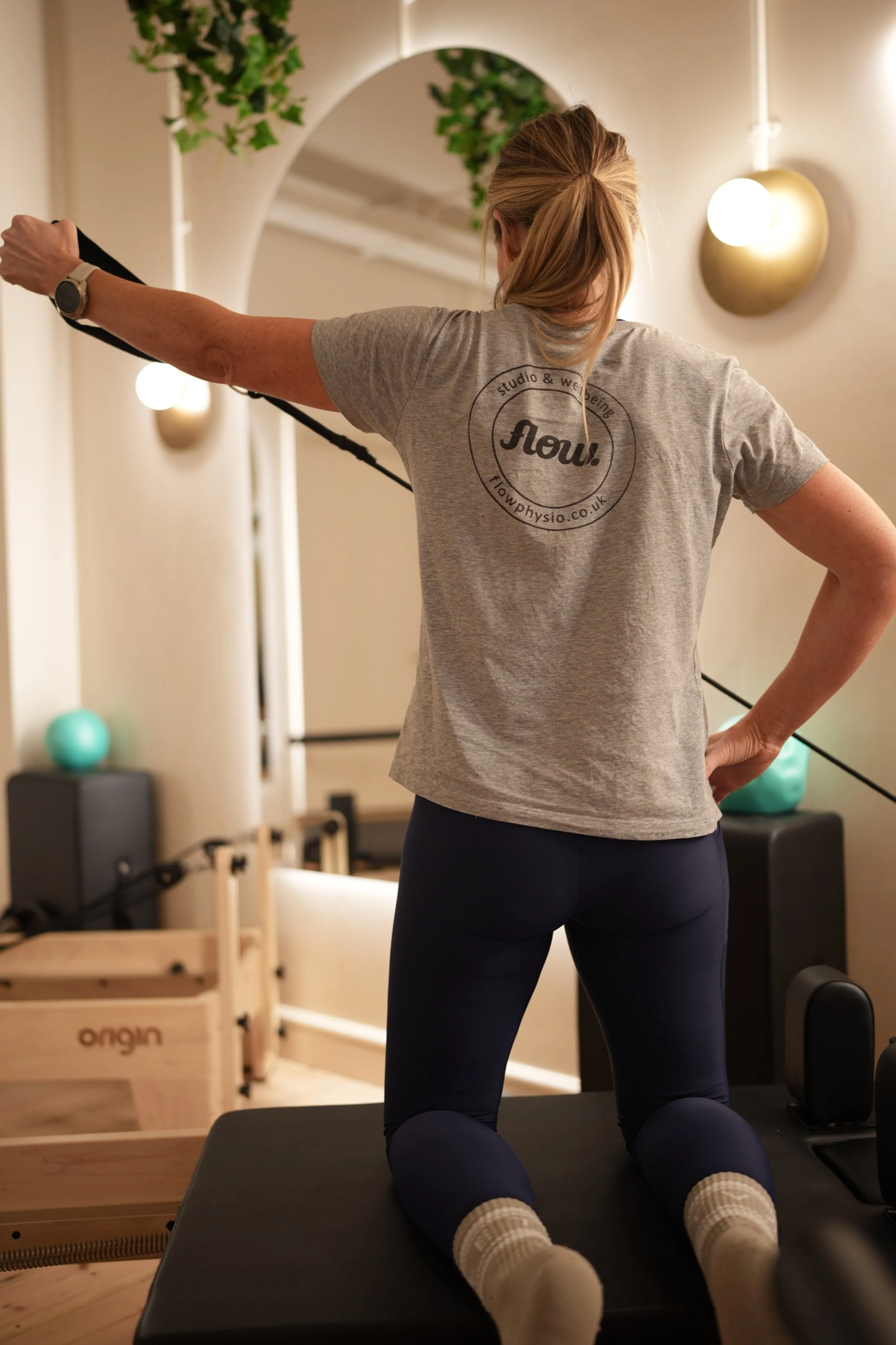 lady doing reformer Pilates holding strap flow studio torquay