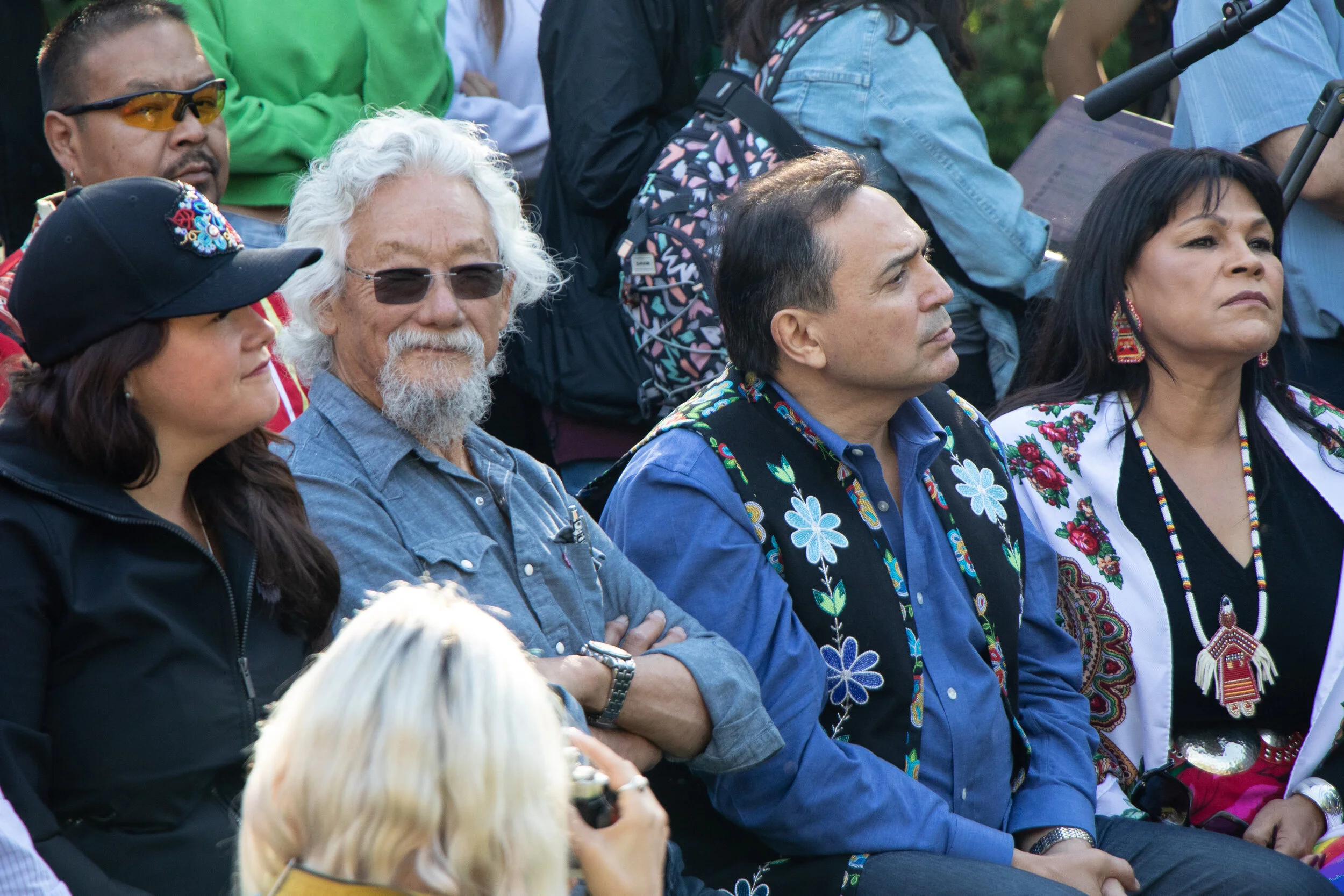 A group of diverse people attending an outdoor event, dressed in colorful and traditional clothing.