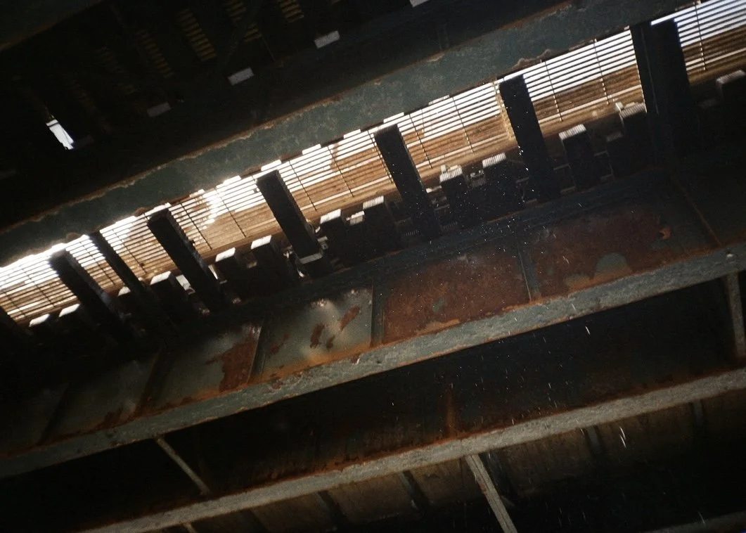 Close-up of rusted metal beams and wooden slats, with some light filtering through gaps.