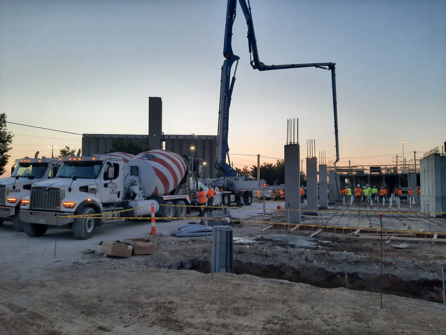 Kienstra mixer trucks delivering concrete alongside a pump at a commercial construction site