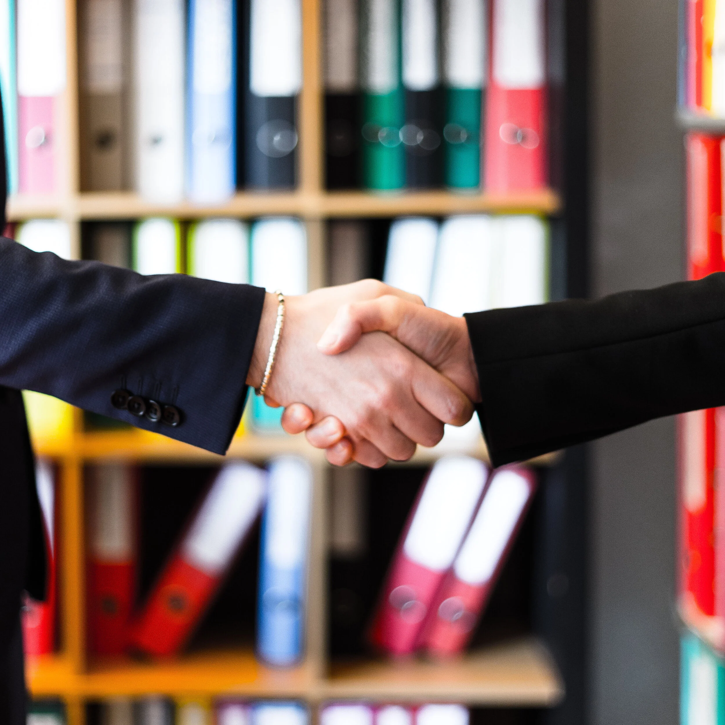 two-person-handshakes-in-front-of-books-on-shelf-2058146 square.jpg