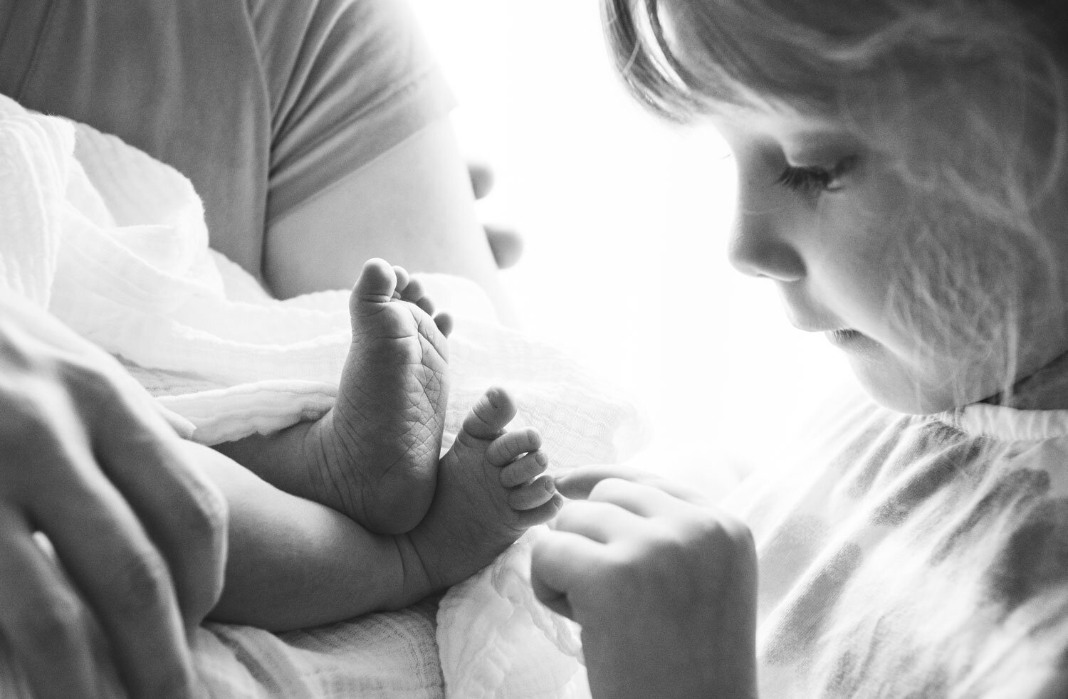 Little girl touching her newborn baby sibling's toe