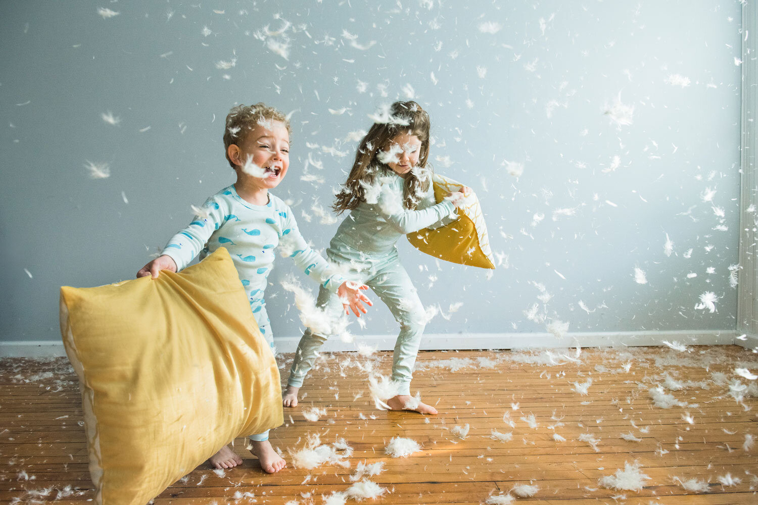 two kids in pajamas having a magical pillow fight with feathers flying
