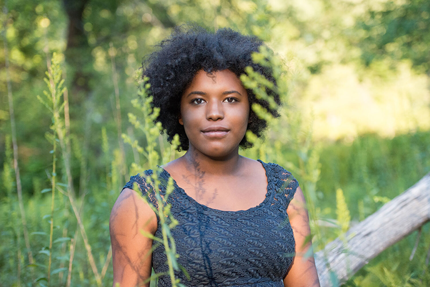 black high school senior woman standing in a field surrounded by greenery