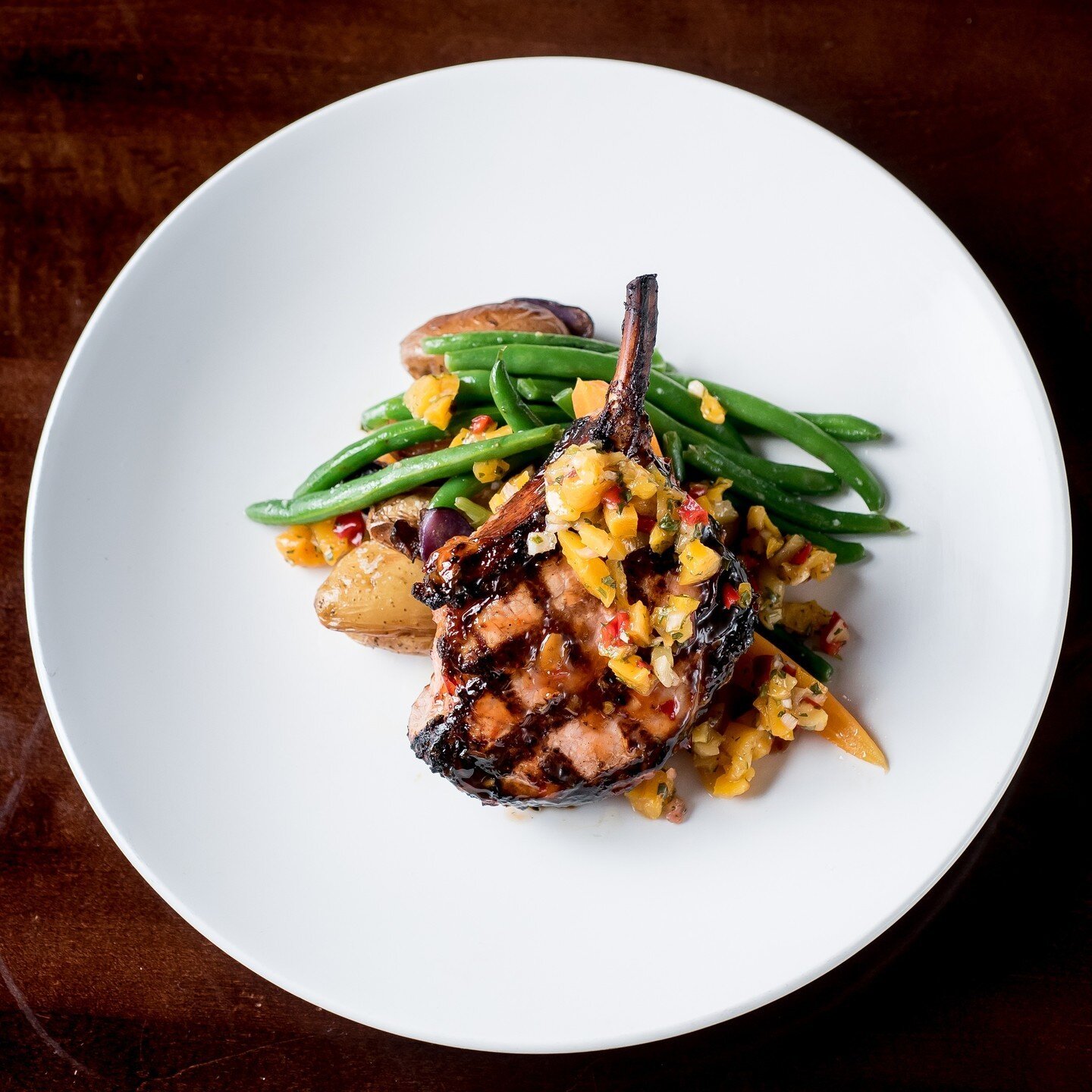 Our Spring menu is back tomorrow! You'll find some new fresh flavors to try along with this Grilled Sweet &amp; Sour Pork Chop with apricot salsa, roasted potatoes, and a seasonal vegetable. ⁠
⁠
We can't wait for you to come in and find your favorite