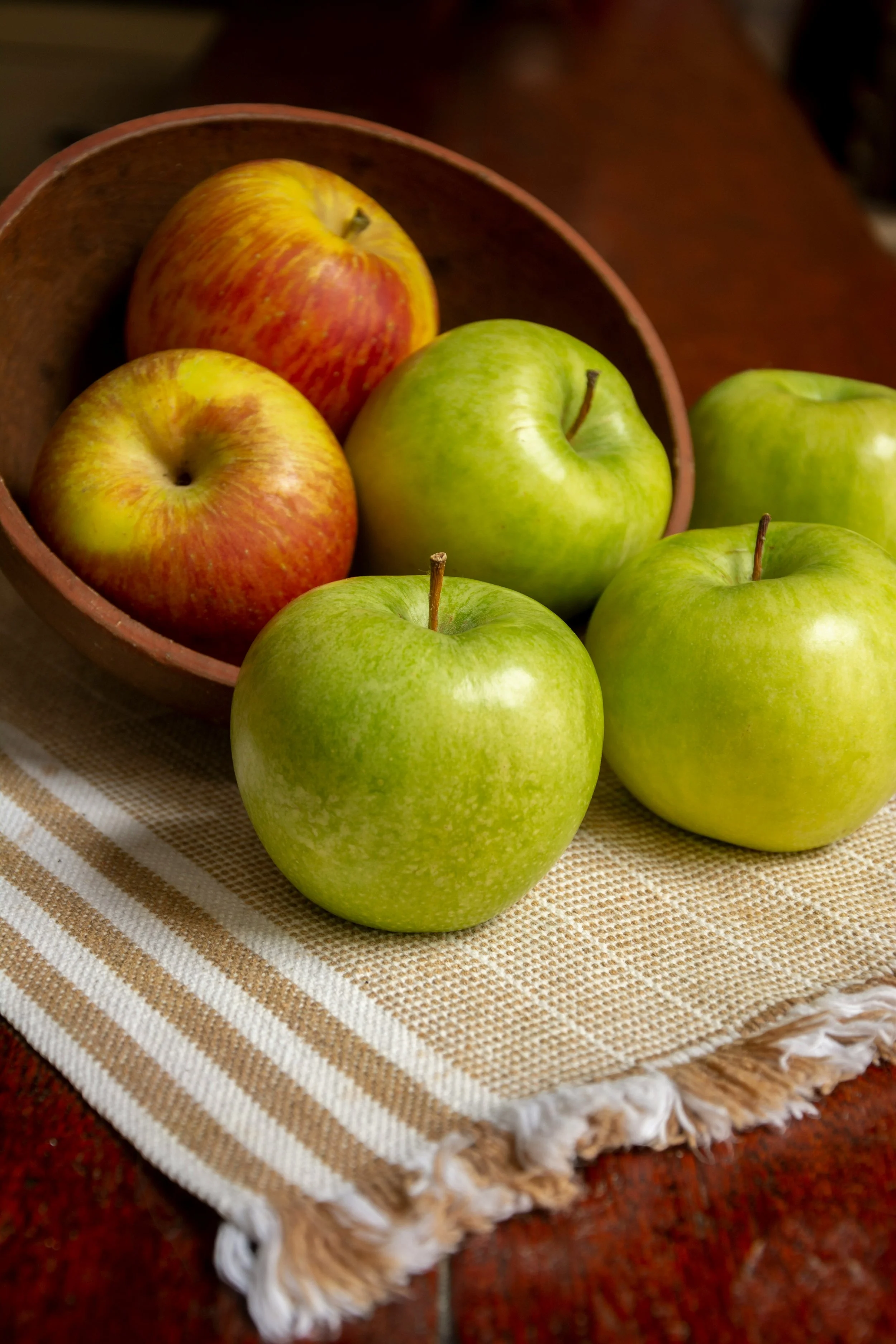 Red and Green apples in a bowl and on a table