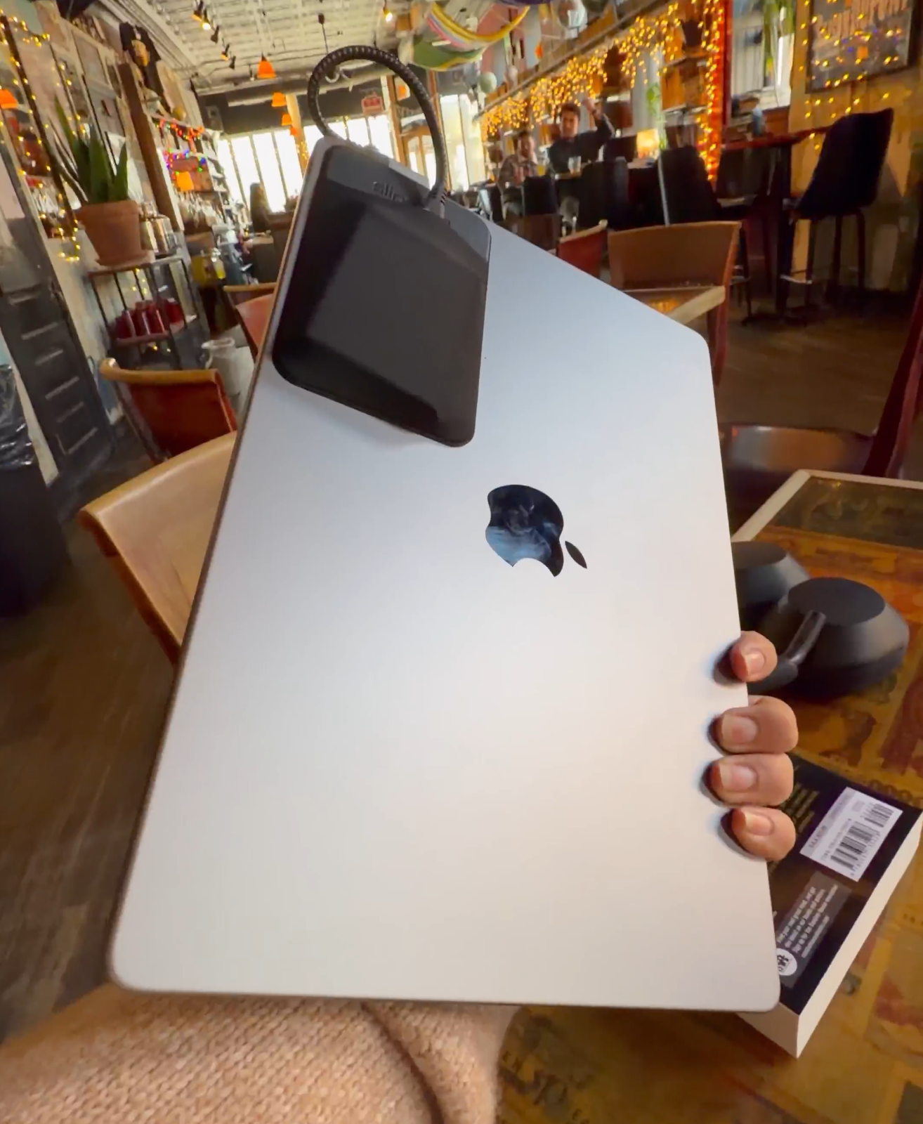 image of laptop closed, with an attached sleeve holding an external ssd and short right angle usb c cable plugged in