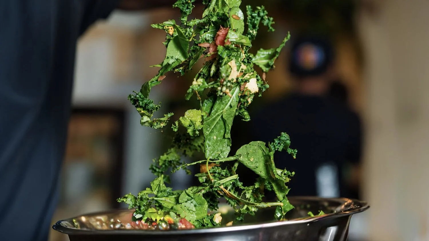 Kale tossed over a steel bowl at the SALATA make your own salad workshop, Alserkal Avenue