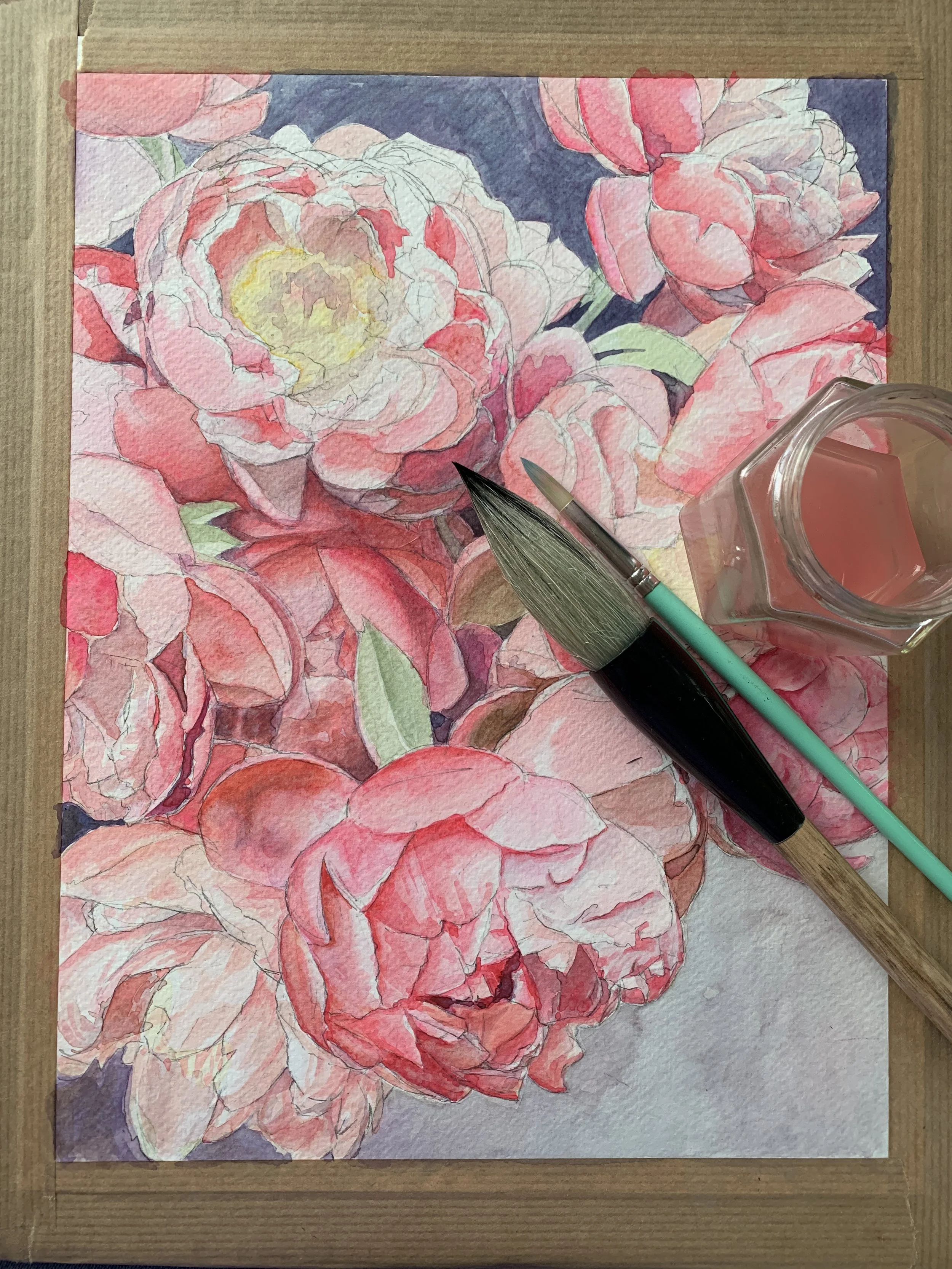 Een aquarelschilderij met bloemen van pioenrozen, omringd door penselen en aquarelverf.