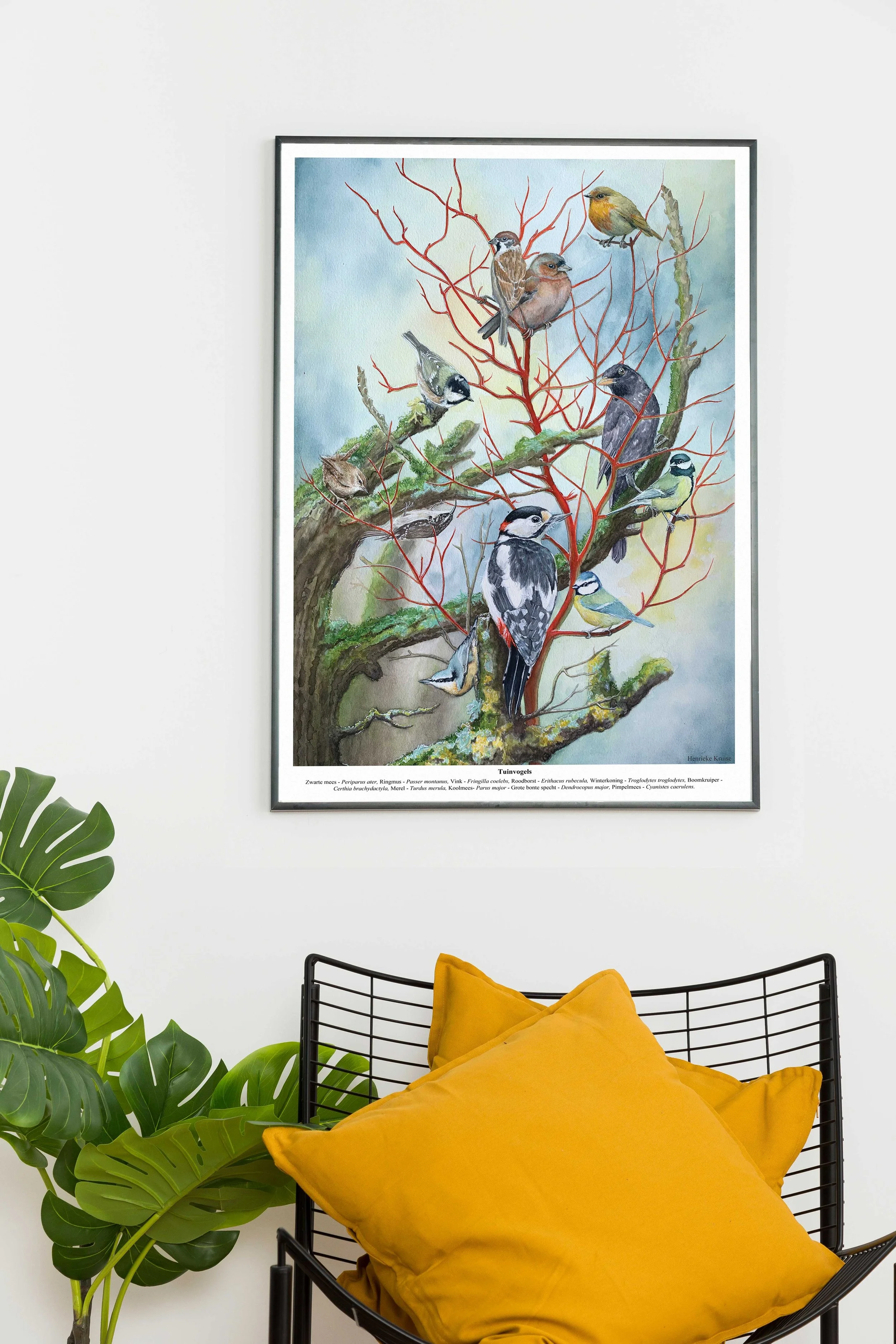 Een kunstwerk van vogels op een tak hangend aan een witte muur in een leefruimte.