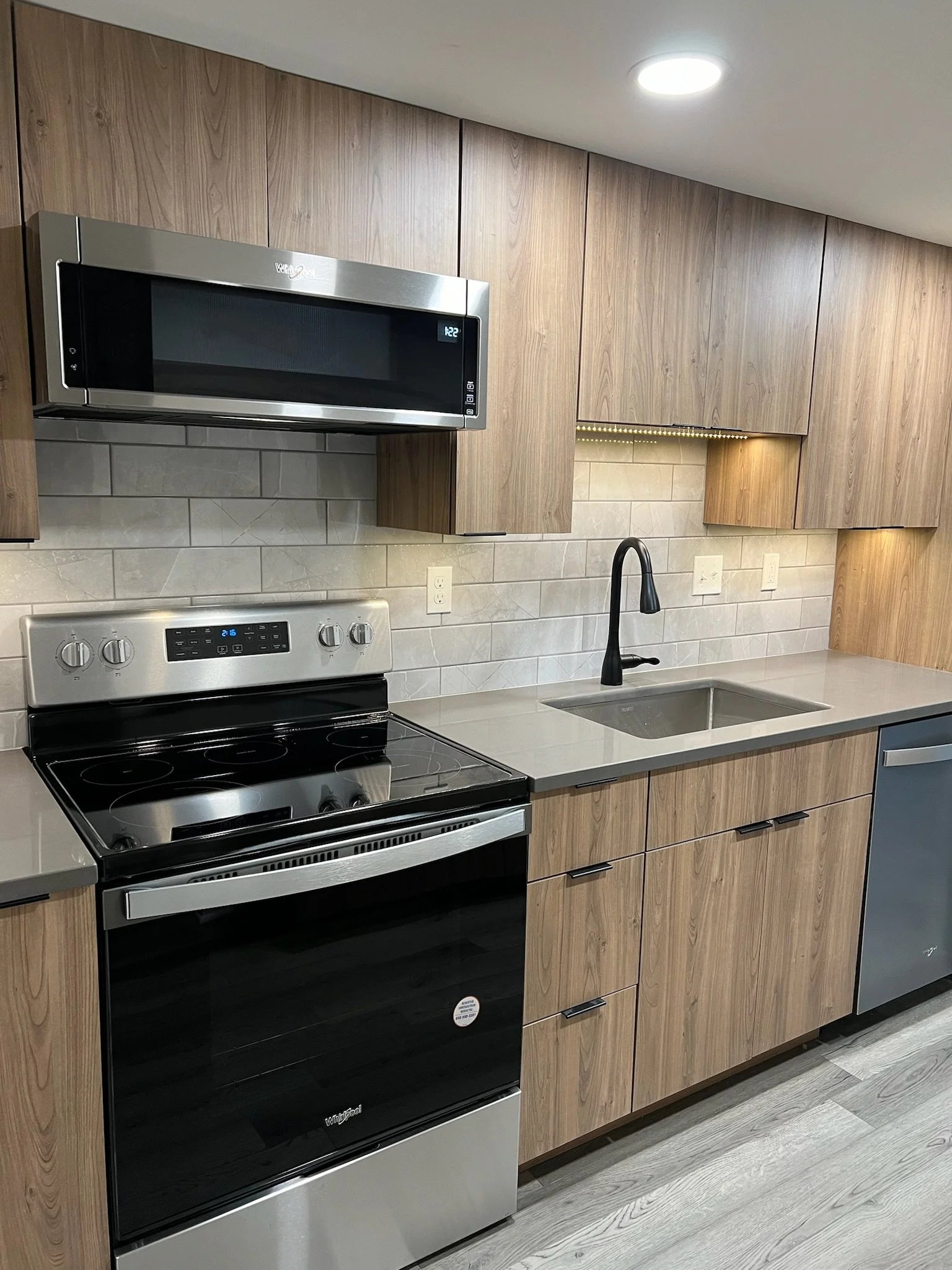 Updated kitchen remodel with under cabinet lighting, warm wood cabinets and grey tile backsplash