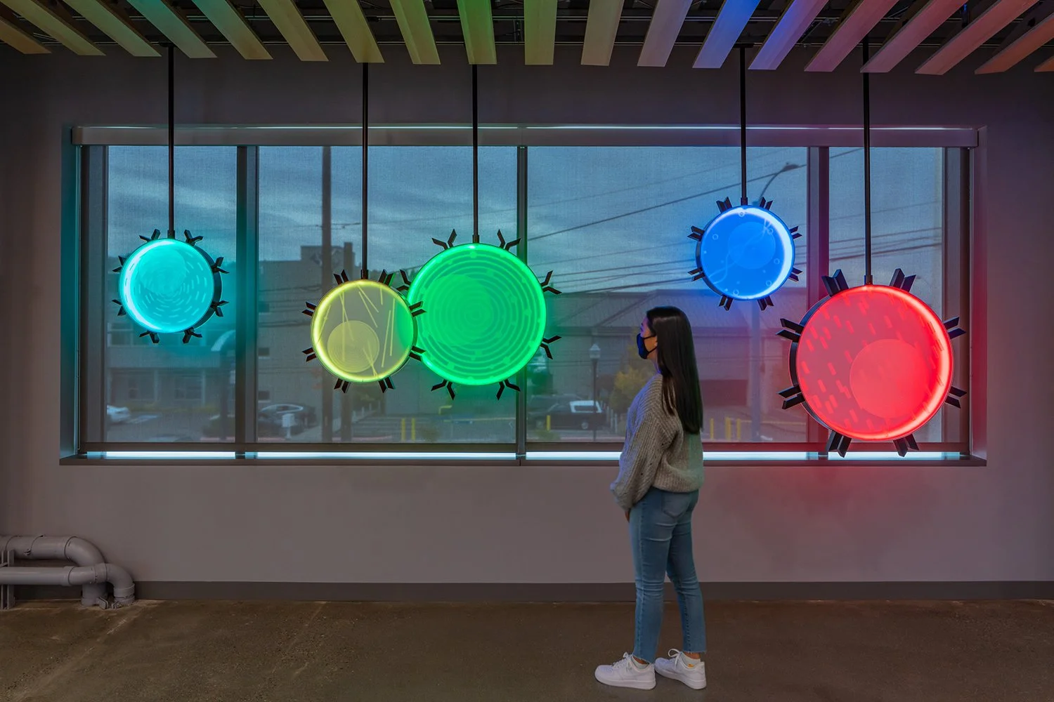 Colorful circular art installations with a woman observing them.