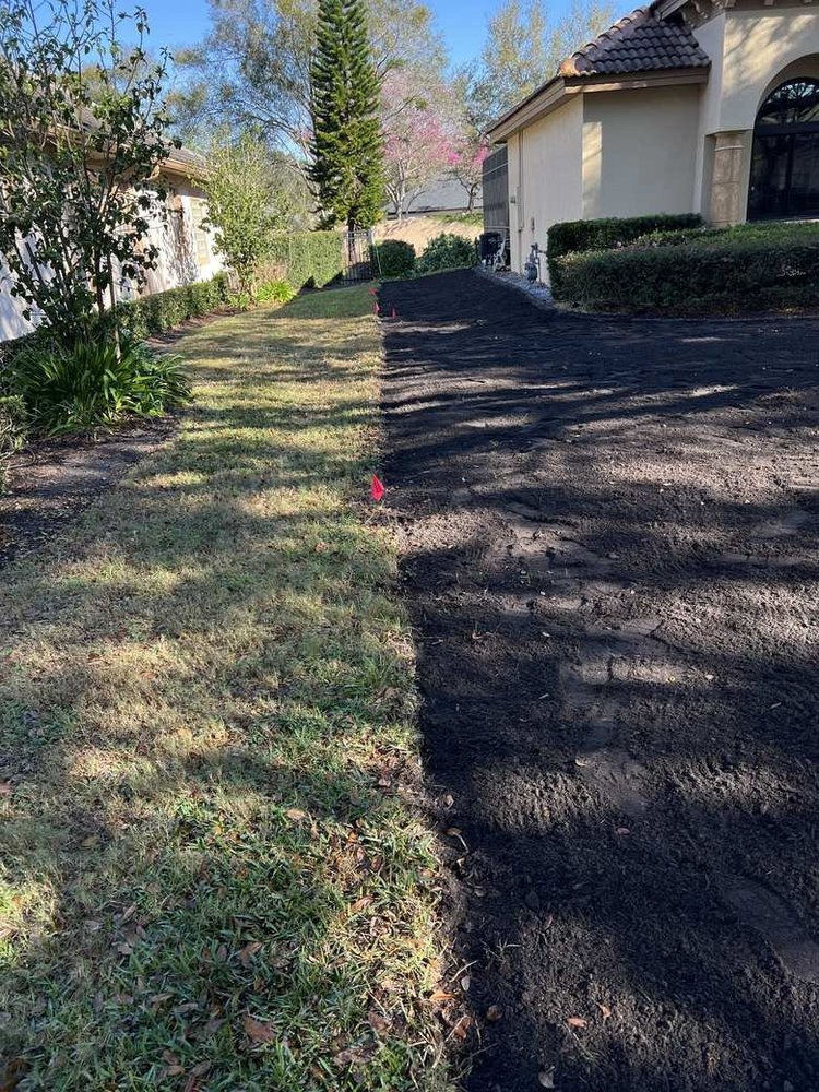 Side yard with old grass removed and dark compost-amended soil prepared for new sod in Central Florida