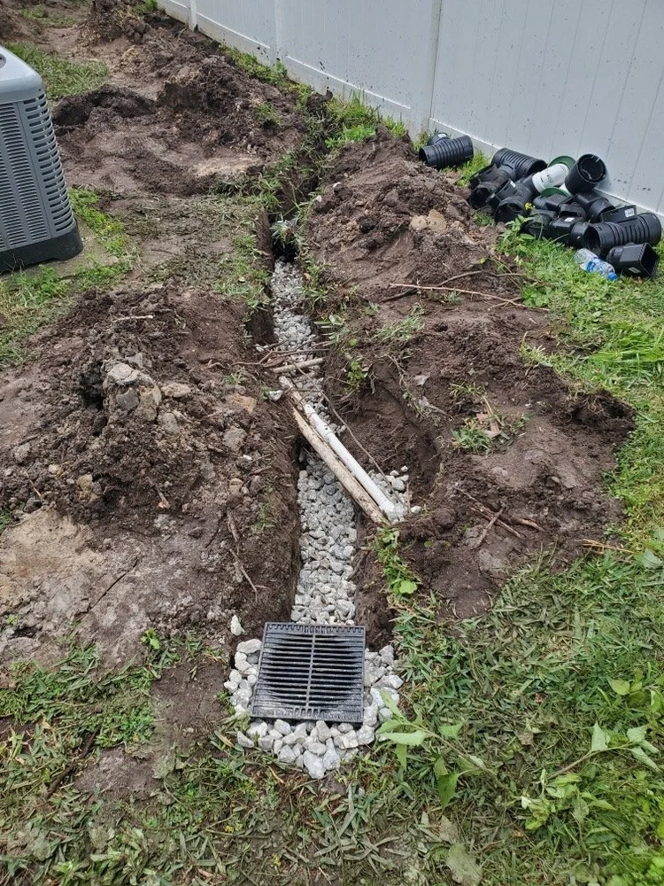 Catch basin grate set in gravel at the start of a French drain