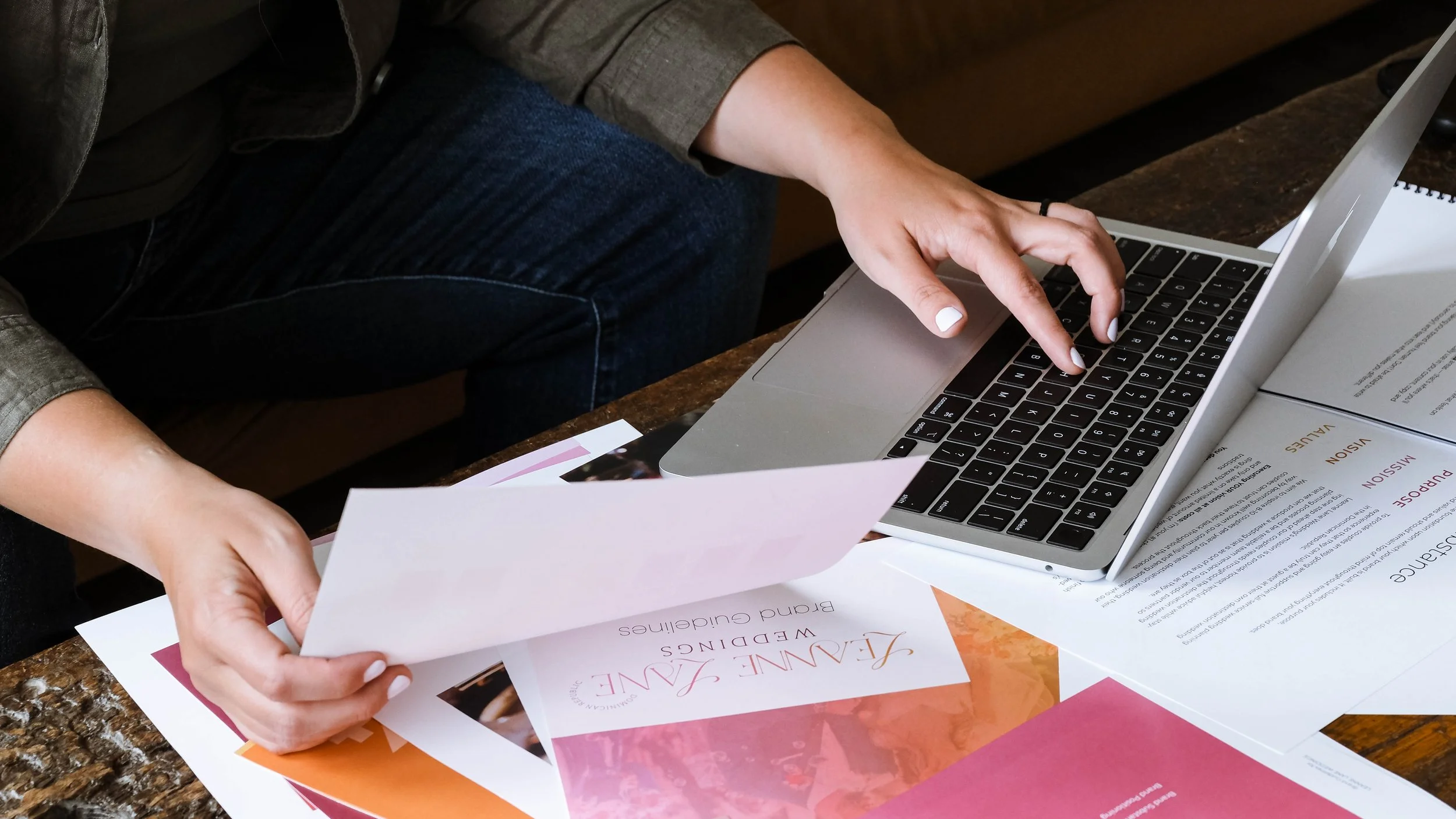 Woman working on laptop and holding brand style guide