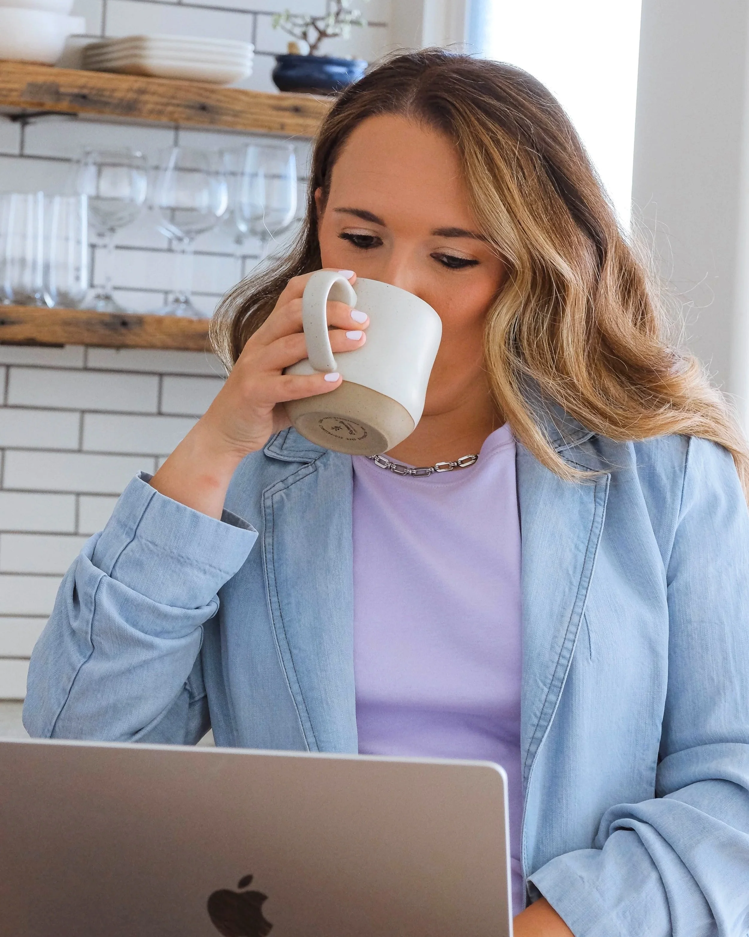 Brand designer Morgan Specht drinking coffee and working on laptop