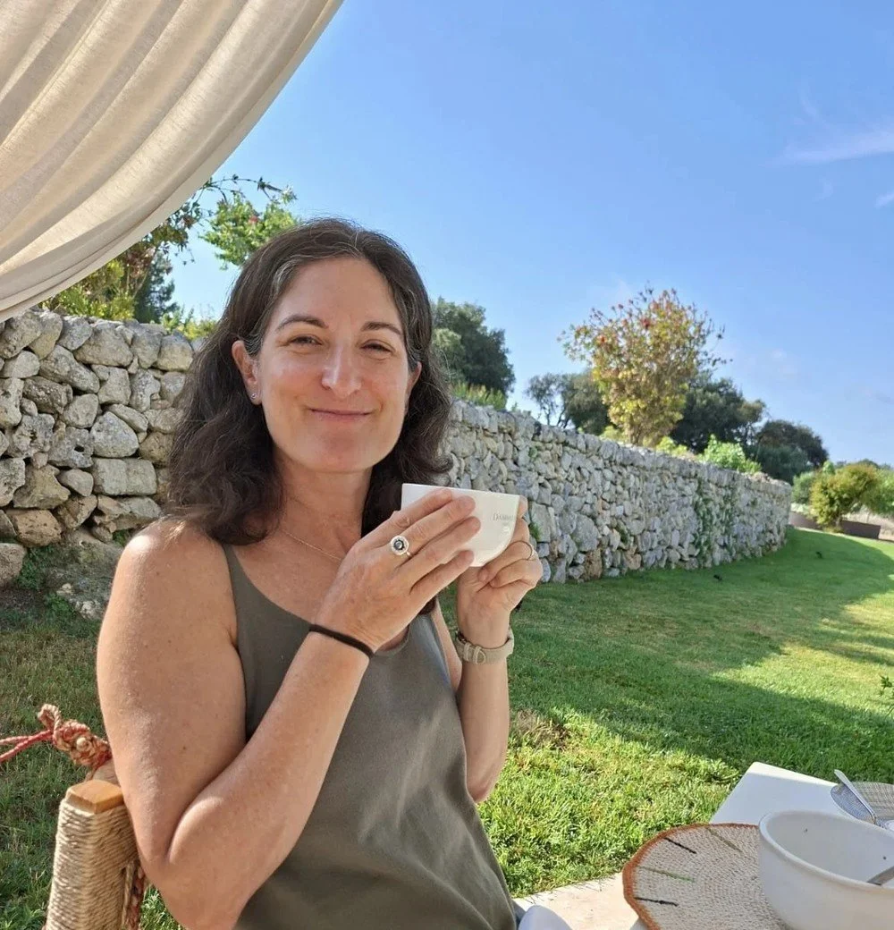 Zoe Kanat smiling and holding a cup of tea outdoors, building a new daily habit