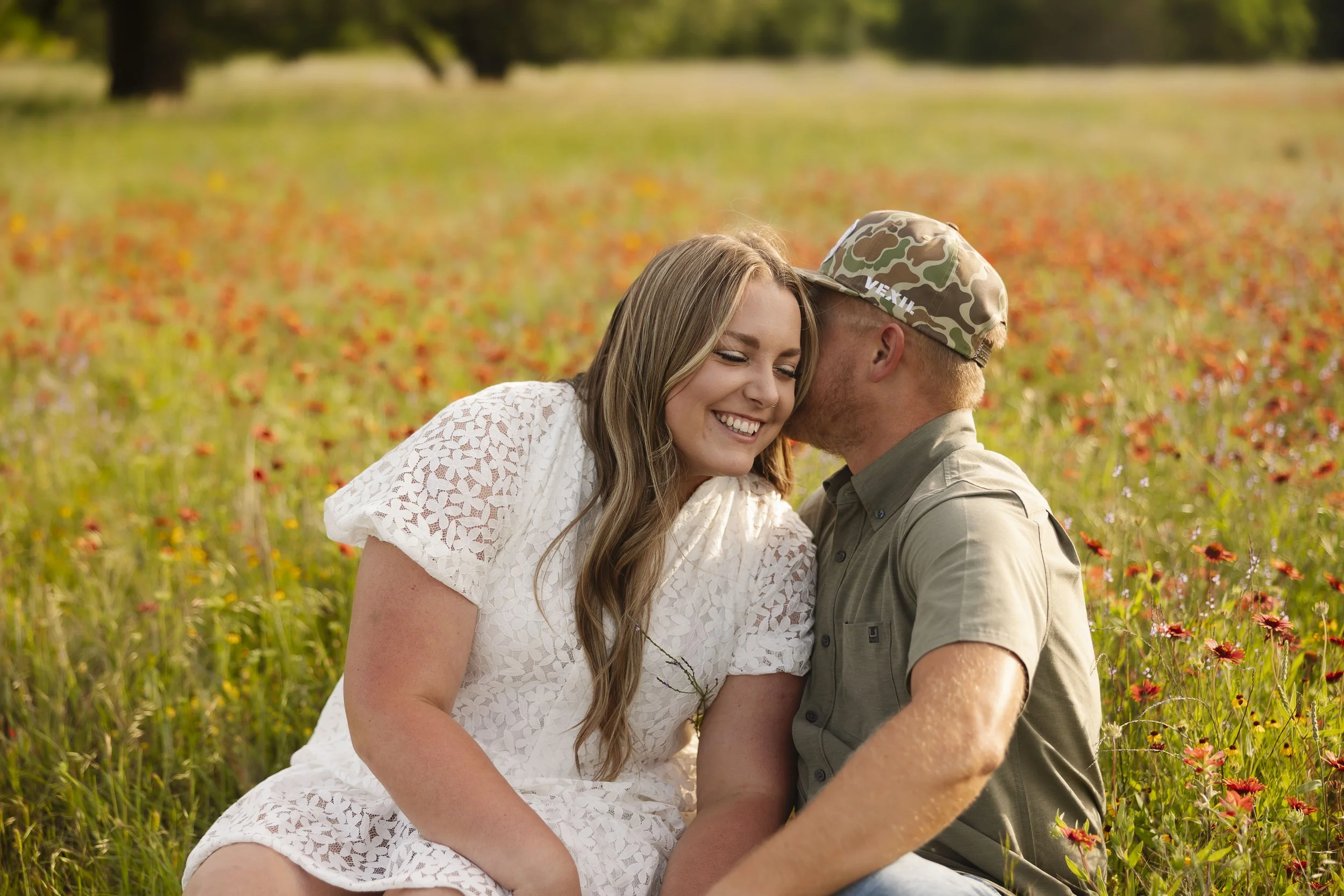 Couple sitting in wildflower field at Sparrow Creek Ranch for their engagement photos.