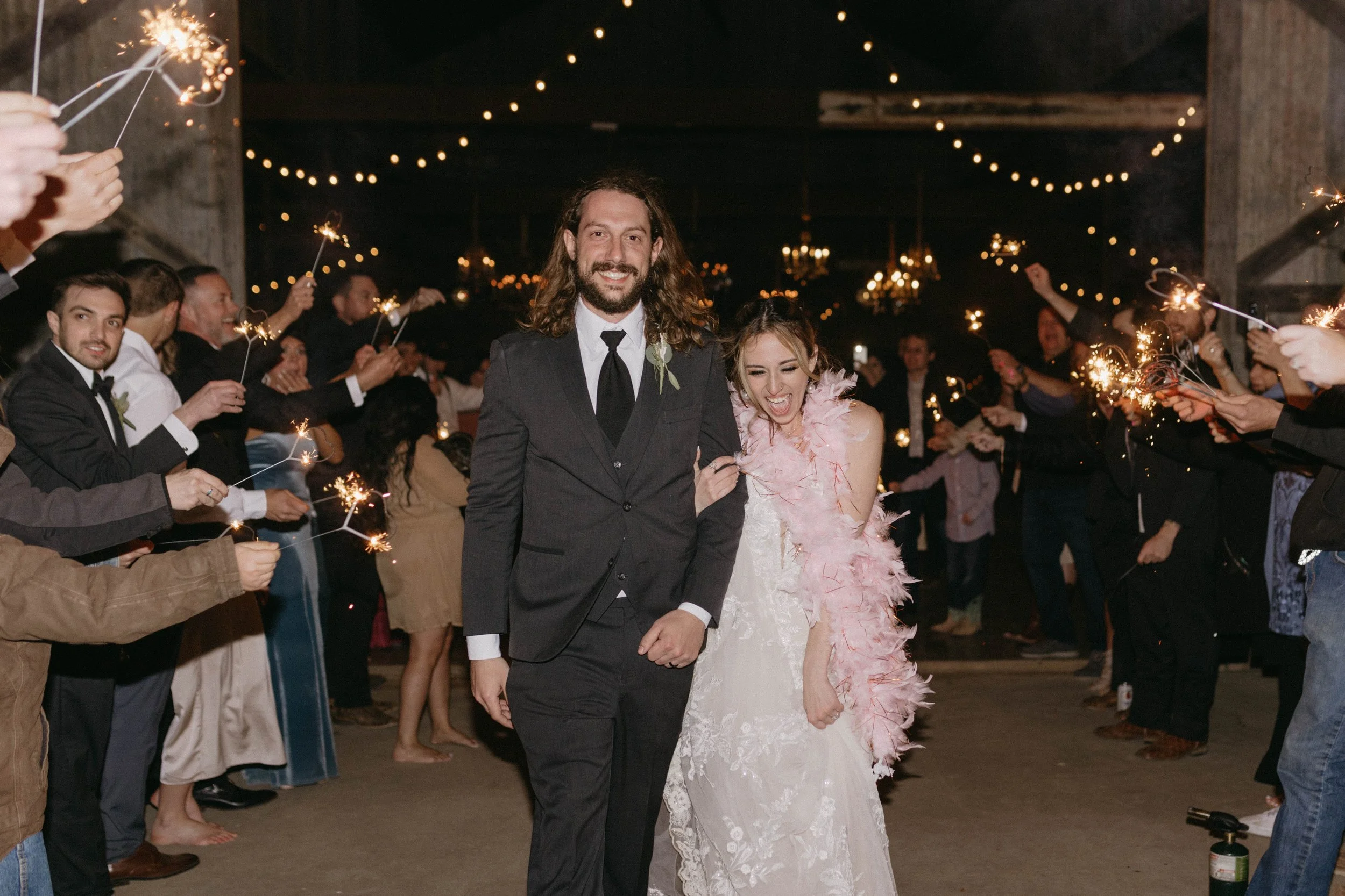 bride wears a pink feather boa as she exits her wedding reception
