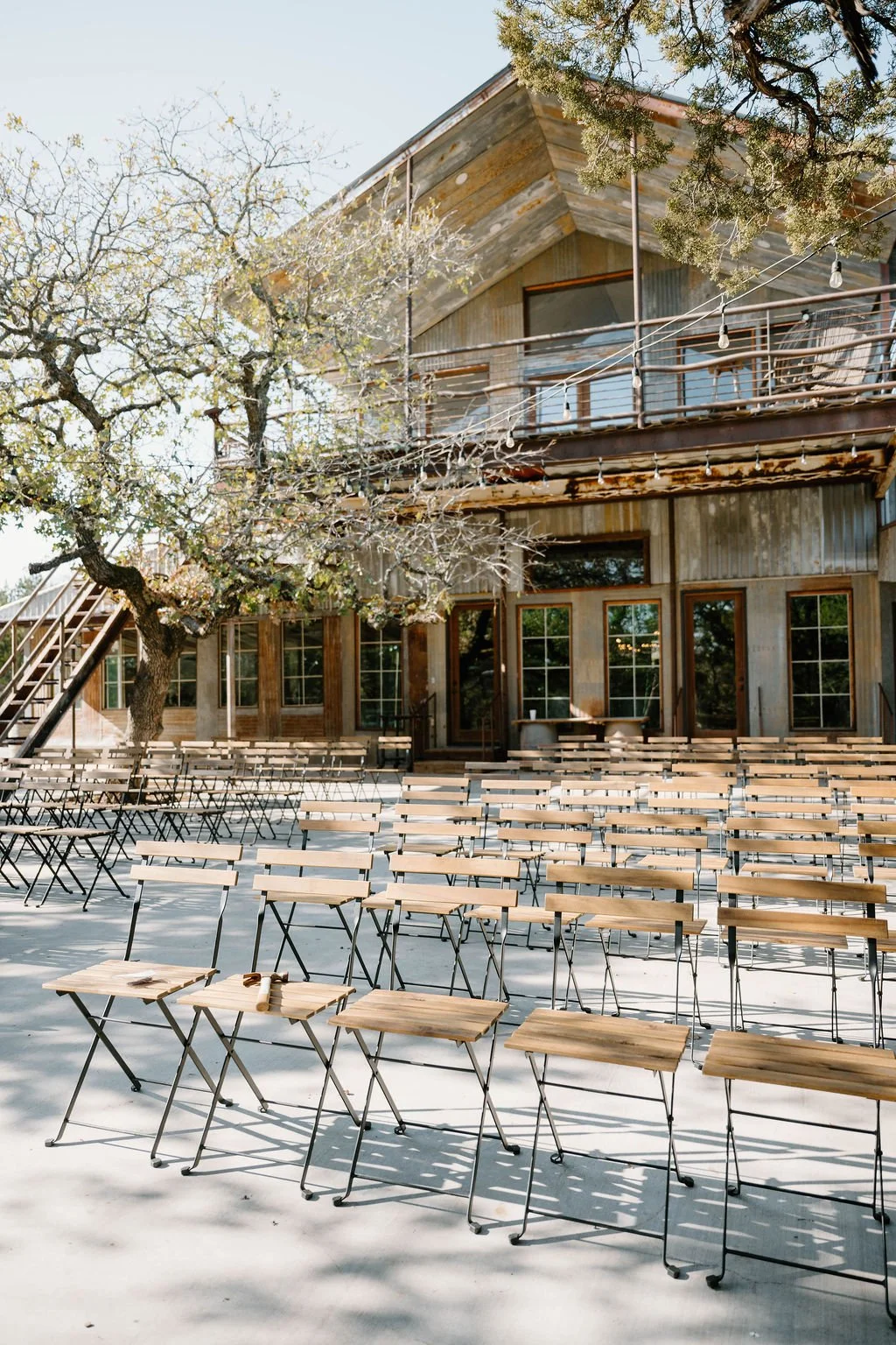 December ceremony setup with chic bistro chairs, beautiful green trees all around the seating, and great sunlight shining down at Sparrow Creek Ranch.