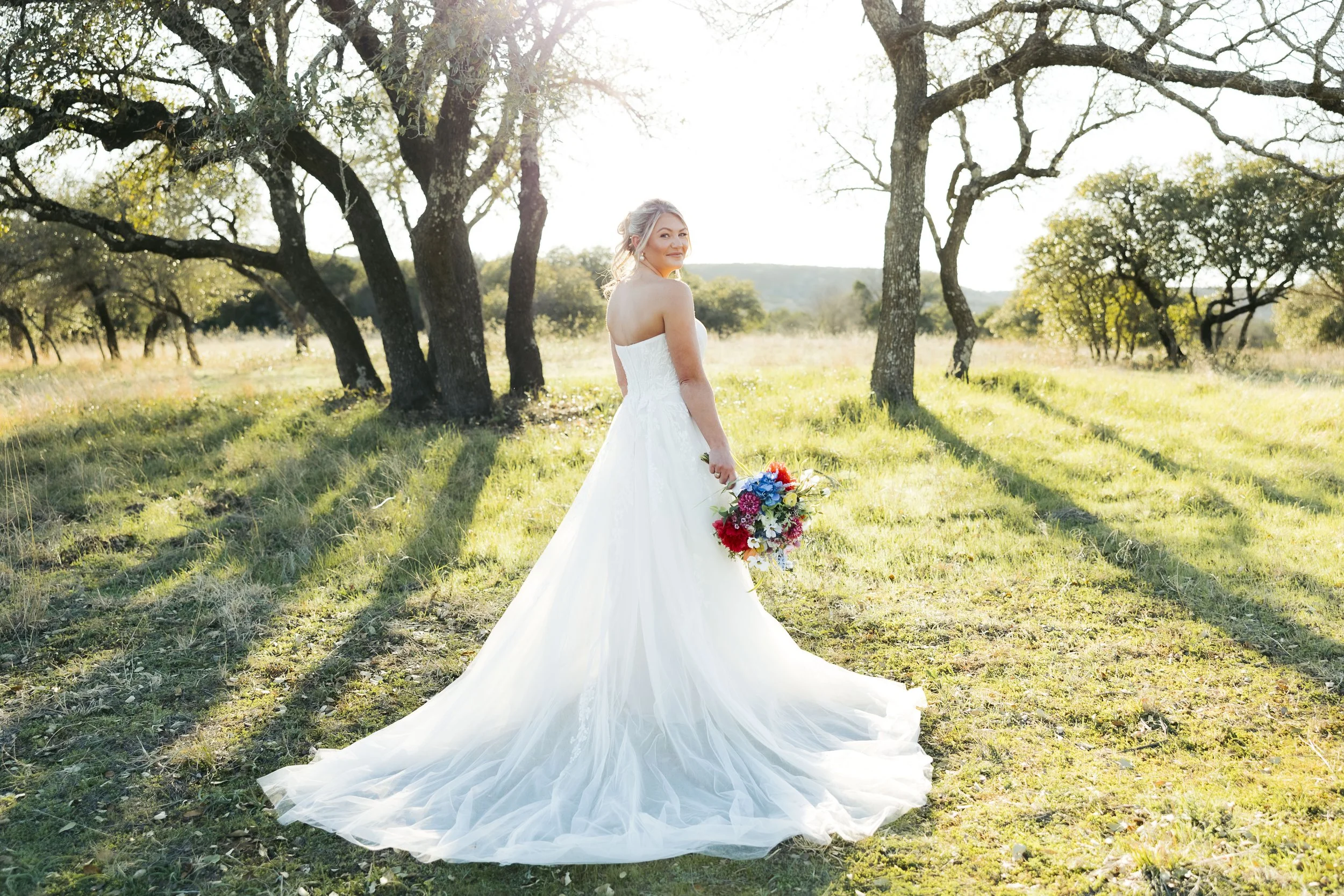Bride looking over her shoulder on a hillside at Sparrow Creek Ranch wedding venue. The Hilltop is a favorite spot for photos.