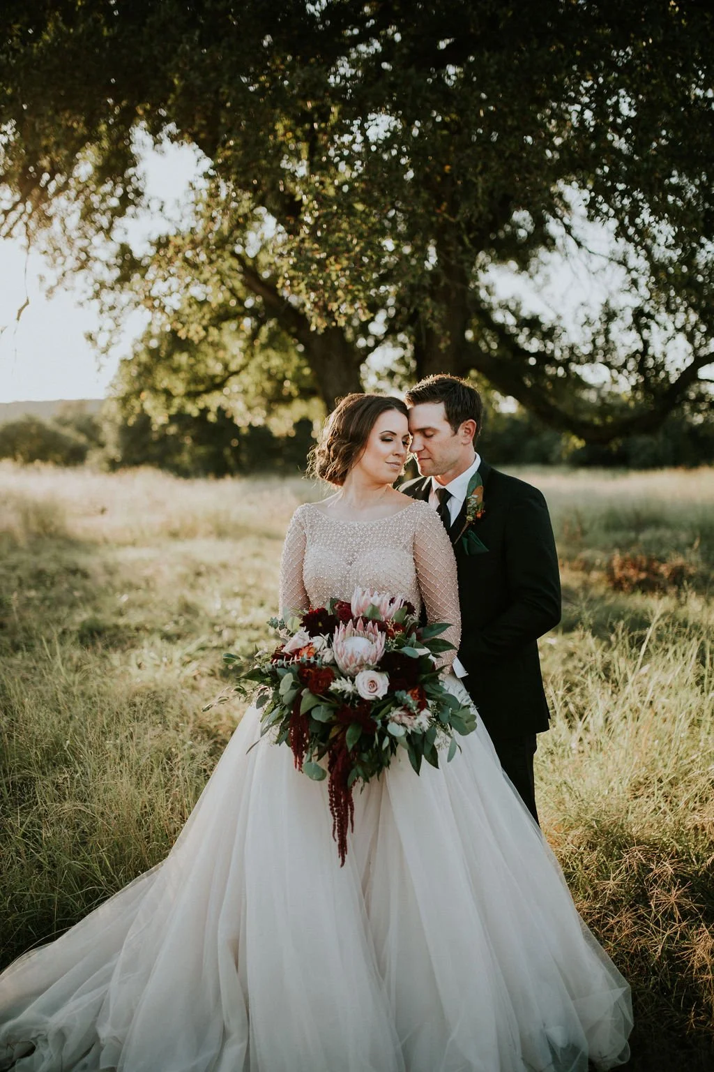 Vintage glam bride with beaded jewel ballgown dress in a field of tall fall grass at Sparrow Creek Ranch wedding venue near Weatherford, Texas.
