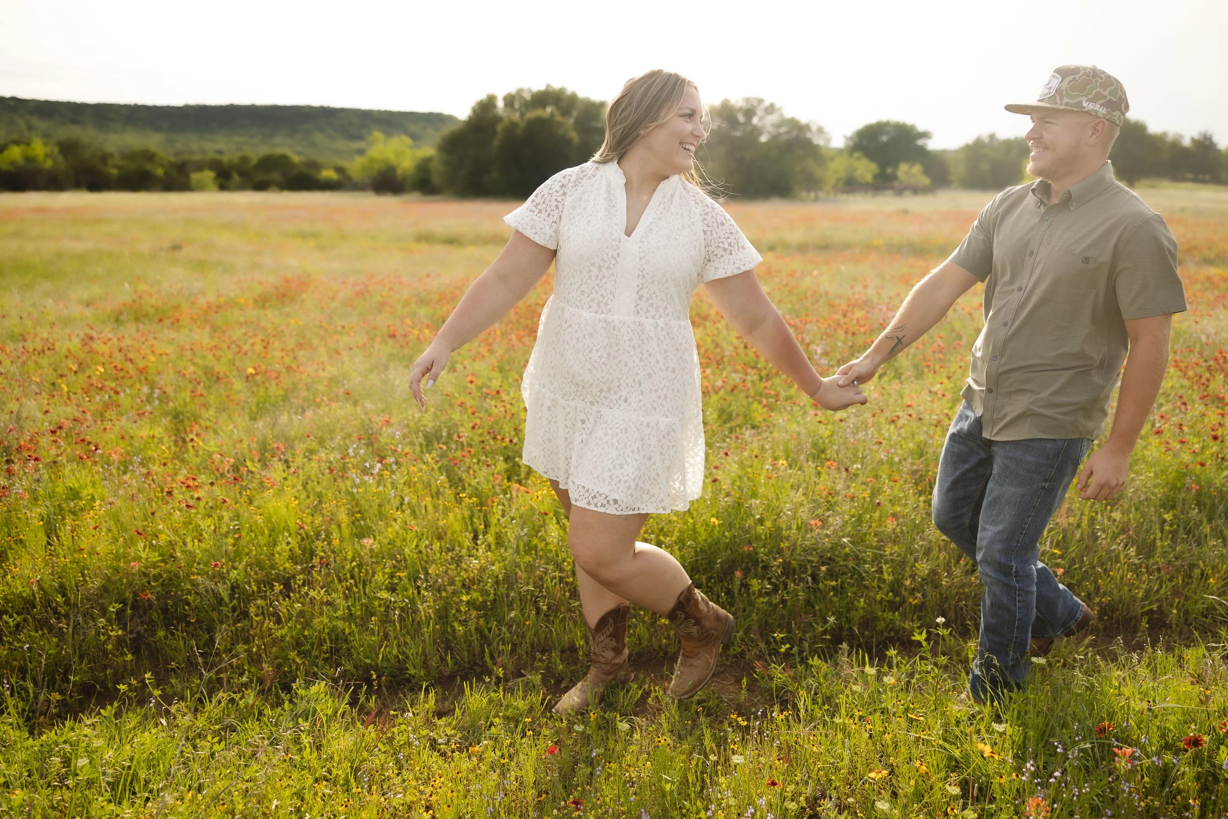 Couple walking through big field of wildflowers for their engagment photos for their wedding at ranch wedding venue Sparrow Creek Ranch.