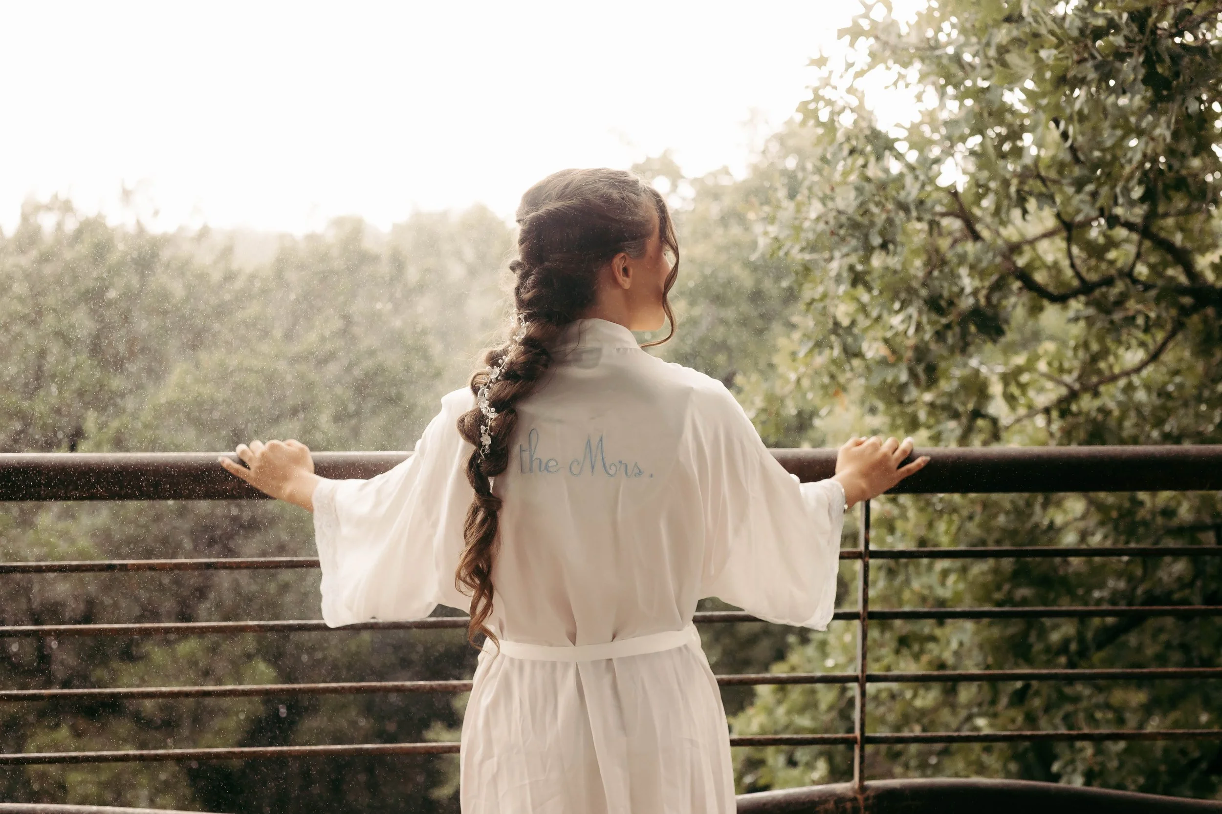 Bride in her robe looking out over the balcony at sparrow creek ranch wedding venue.