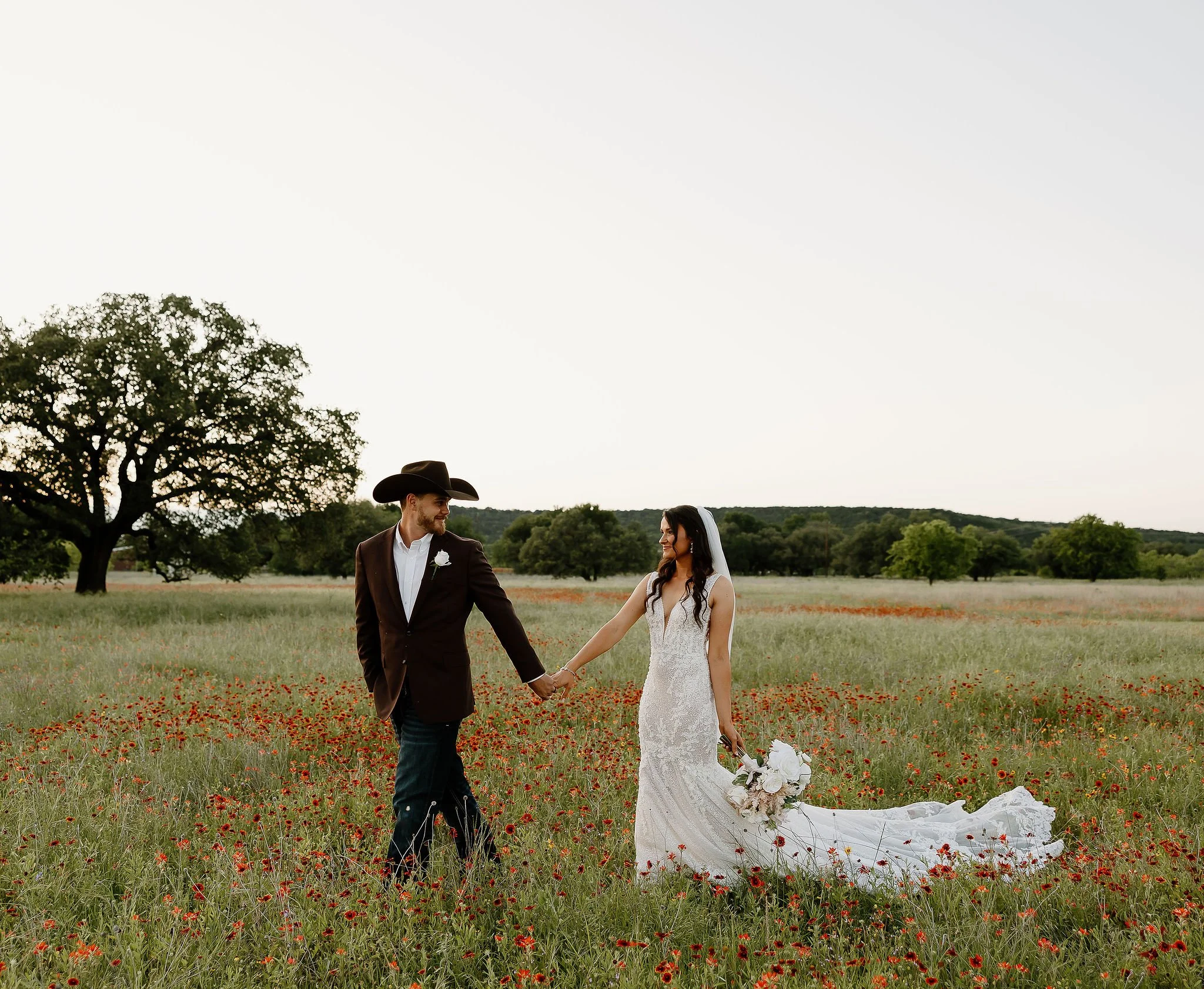Couple walk through wildflowers at thir ranch wedding venue Sparrow Creek Ranch in May peak wildflower wedding season.