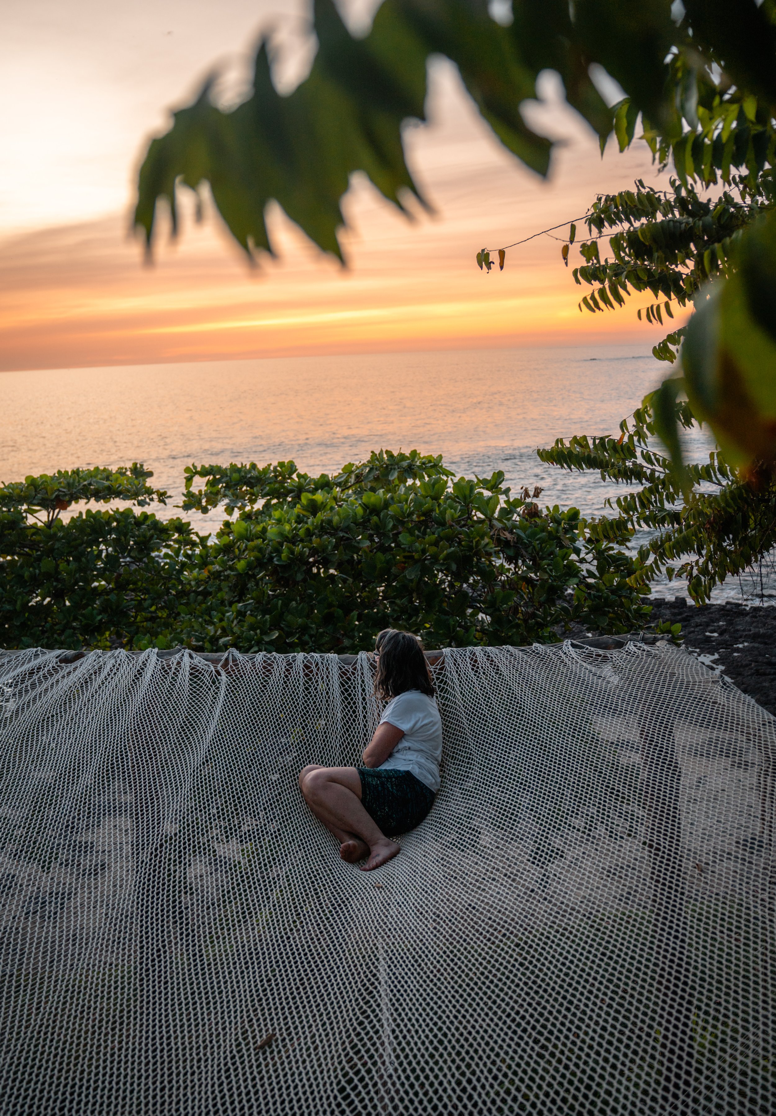 Guest relaxing in the oceanfront net hammock at sunset at Still Salty Escape in Nicaragua