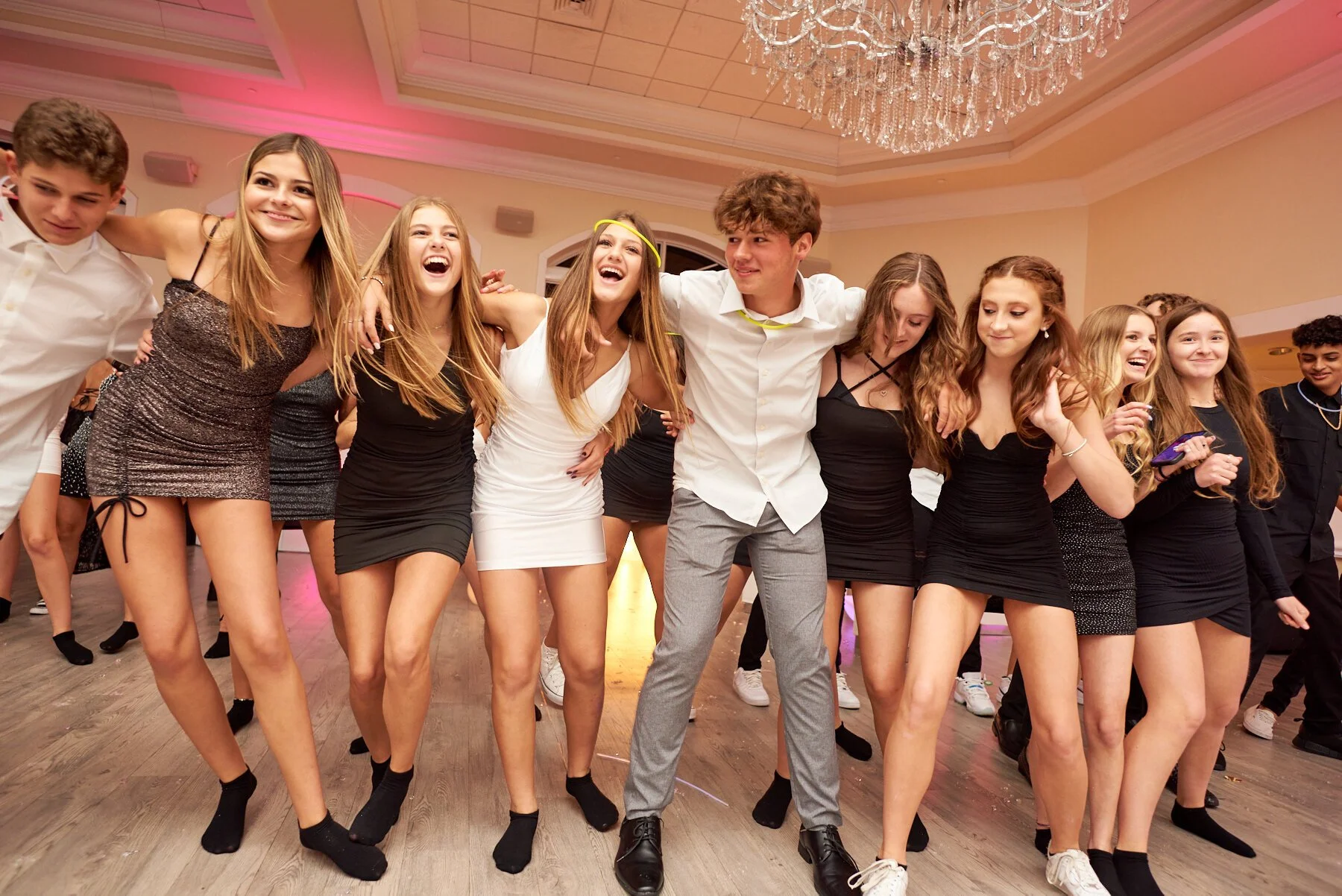 A group of teenagers dancing together at a party or celebration in a decorated hall.