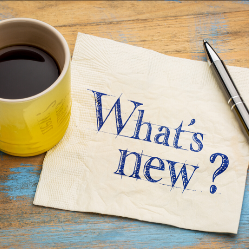 What's New? written on a paper napkin next to a cup of coffee