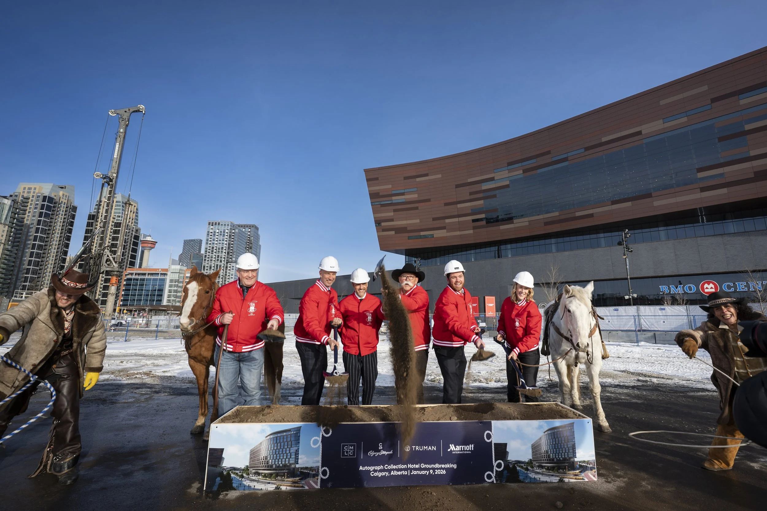 A photo on of the groundbreaking of The Autograph Collection Hotel on Stampede Park in The Culture and Entertainment District. There are trick ropers flanking two horses with representatives scooping dirt with shovels from a sod box.
