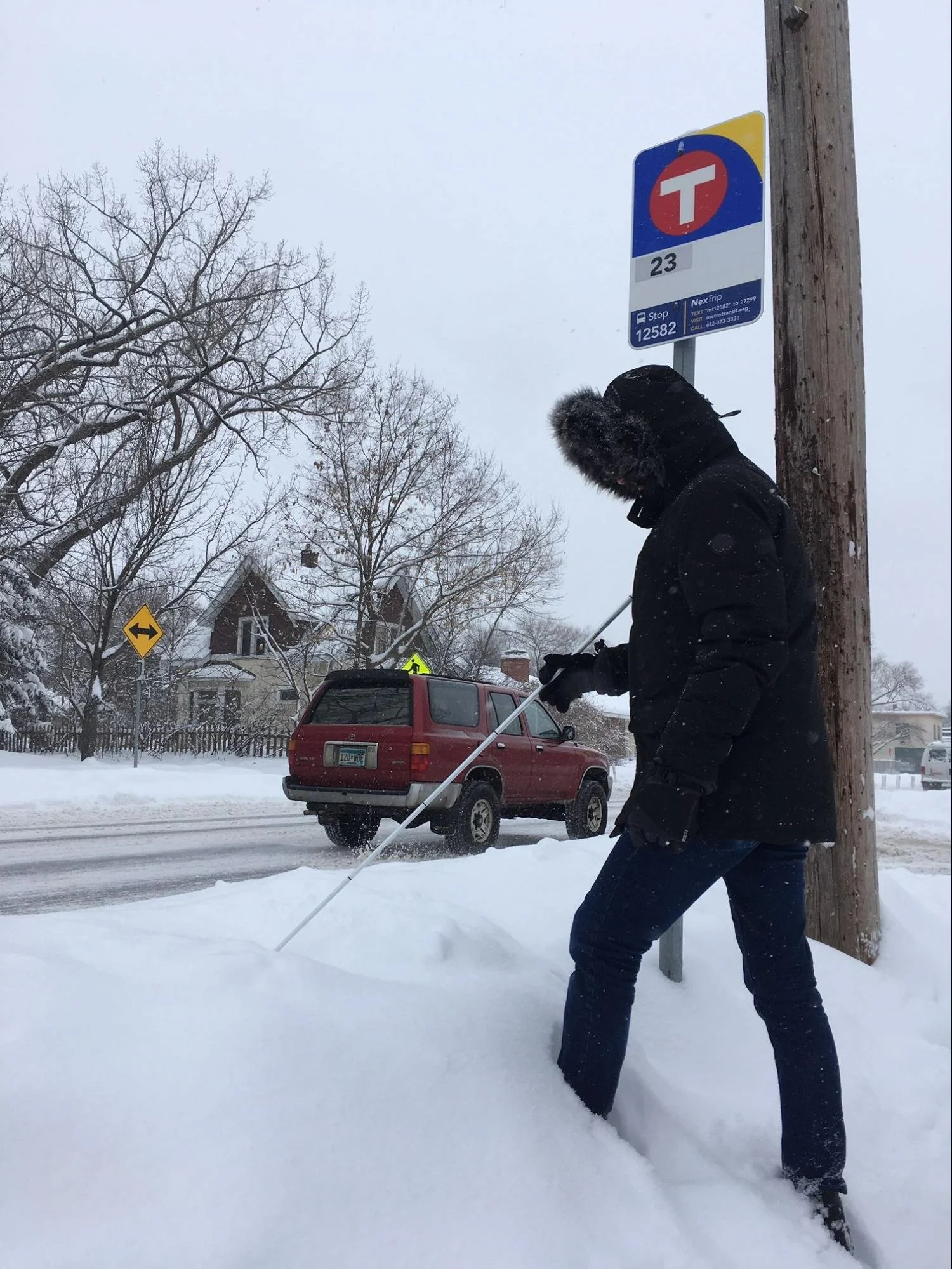 An Our Streets volunteer navigating transit stop piled high with snow
