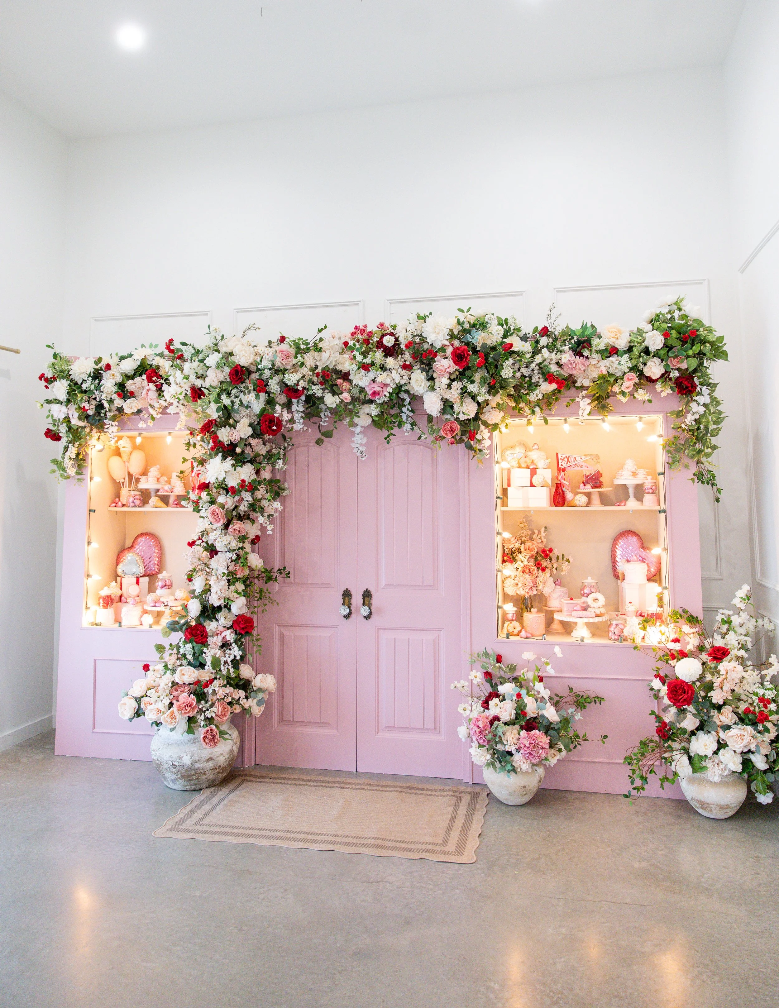 Pink display cabinet decorated with a large floral arrangement of pink, white, and red flowers, highlighting a celebration or event setting.