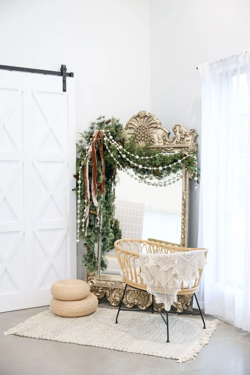 A green vintage-style sofa with gold legs in front of a large light gray wall and white background, with sunlight streaming in from the left.