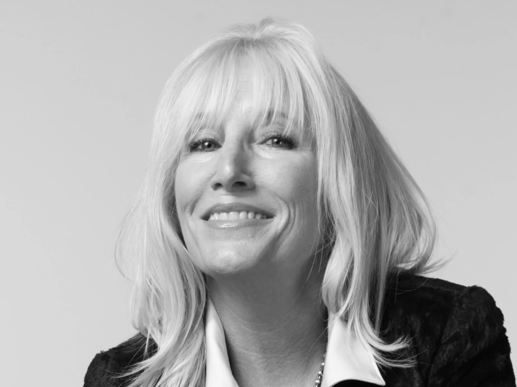 Black and white portrait of a woman with shoulder-length blonde hair smiling at the camera.