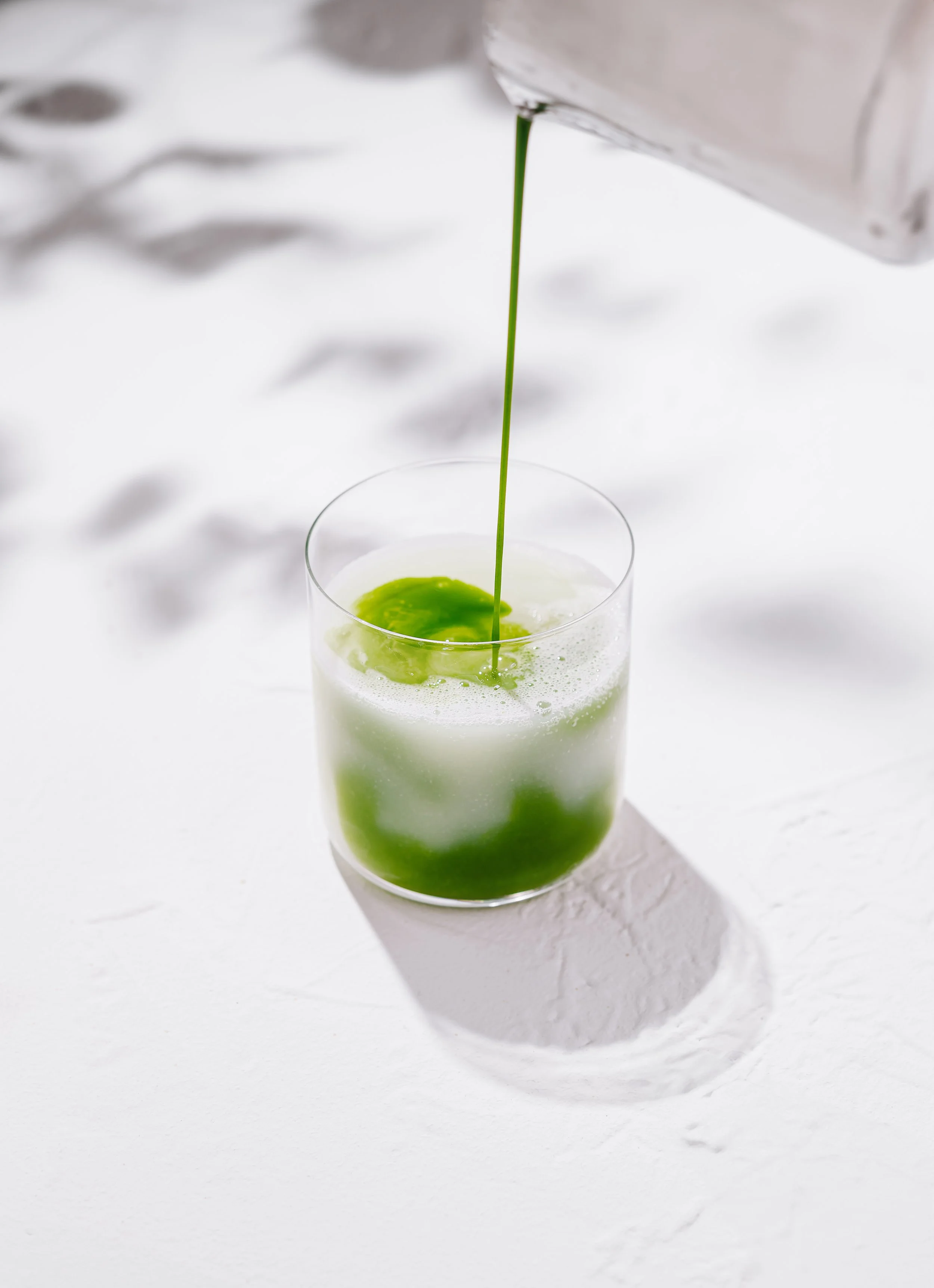 barista-pouring-matcha-latte-glass-white-background.jpg