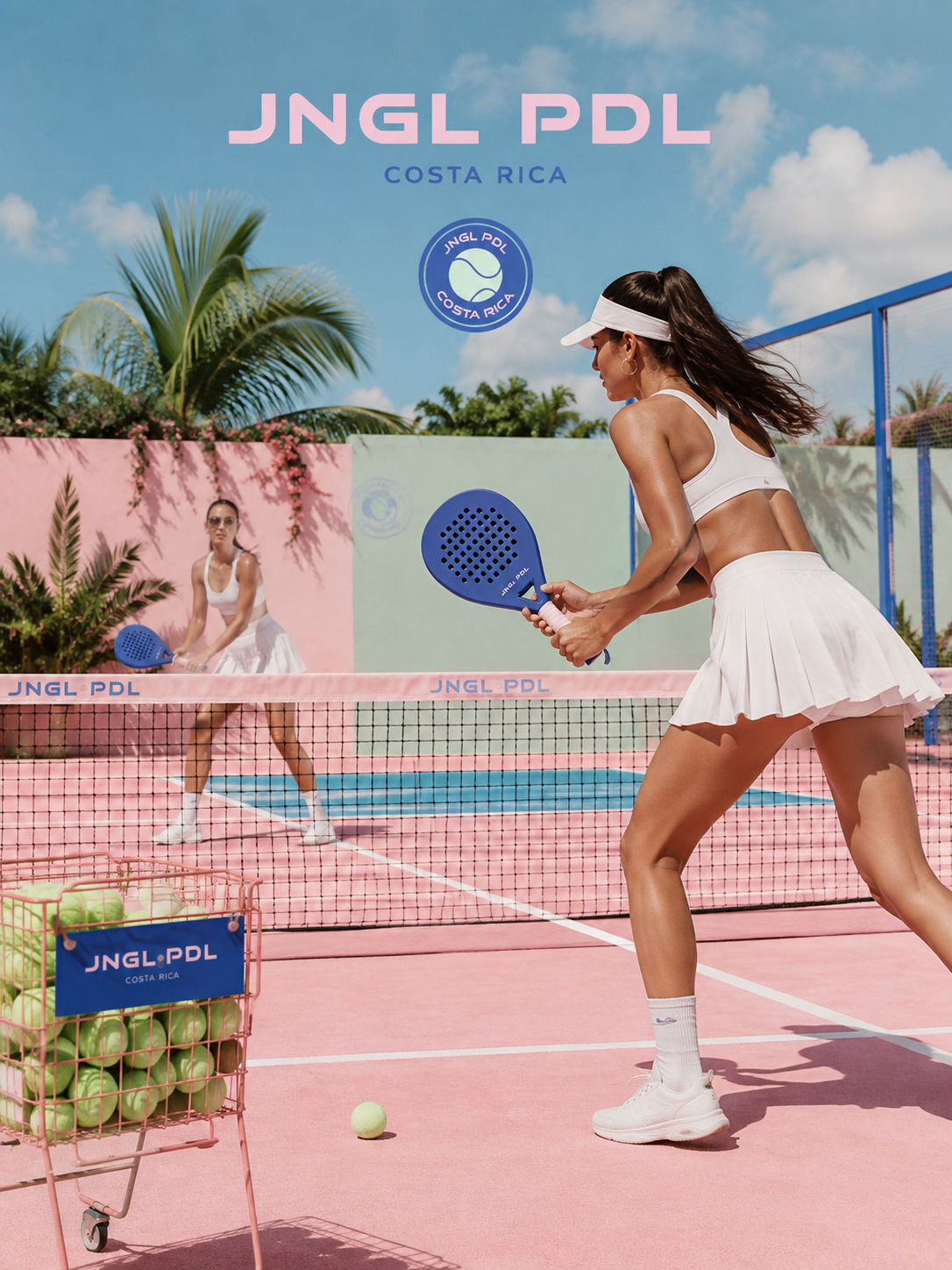 Two women playing pickleball on a colorful outdoor court with palm trees in the background, wearing white athletic clothing and holding blue paddles, with a basket of tennis balls nearby.