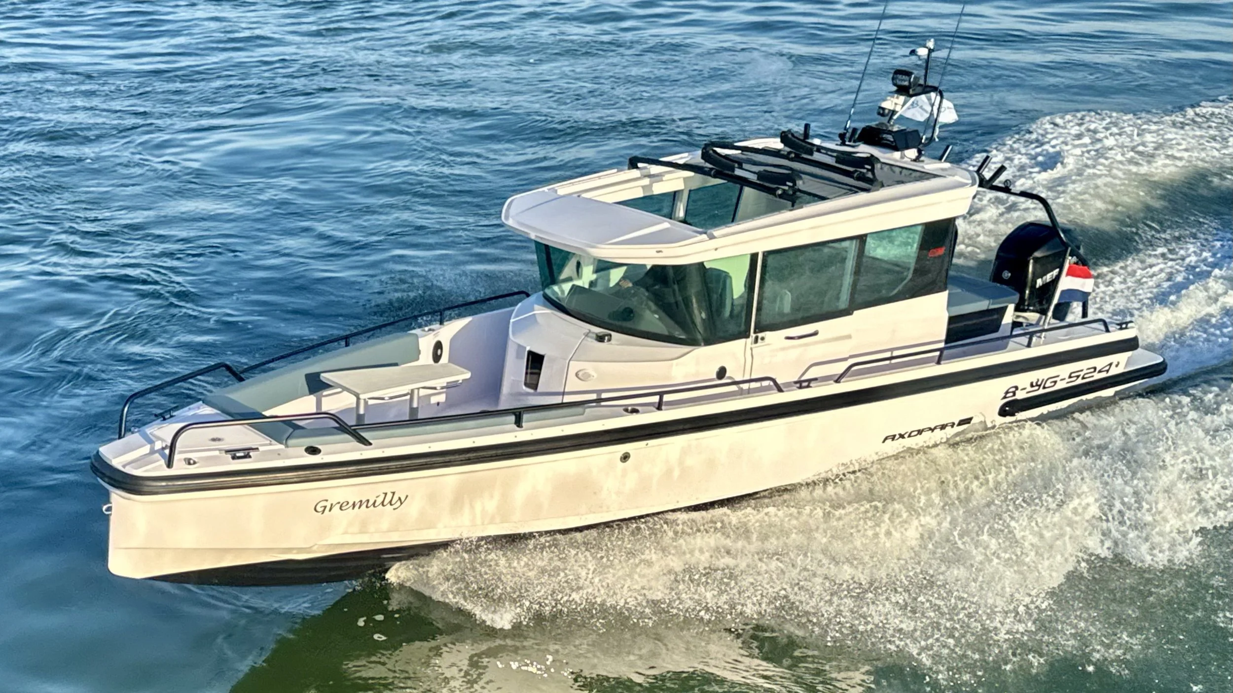 A white motorboat moving on the water with the name Gremilly on the front.