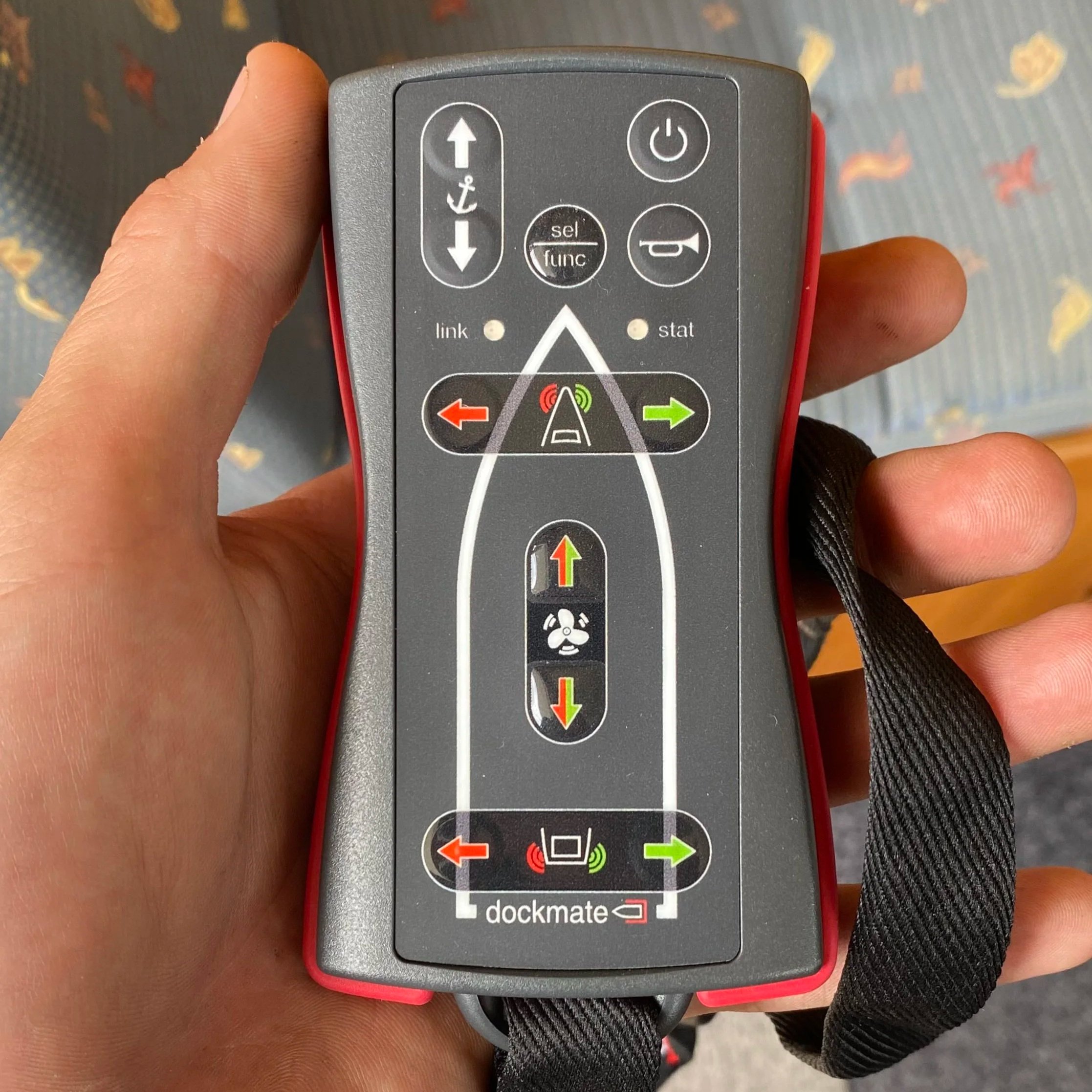 A handheld remote control device with multiple buttons and indicator lights, used for operating marine or industrial equipment, featuring directional arrows, indicator lights, and labels such as 'link,' 'stat,' and 'dockmate'.