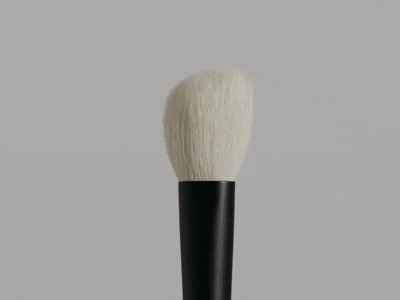 Close-up of a rephr makeup brush with a black handle and white bristles.