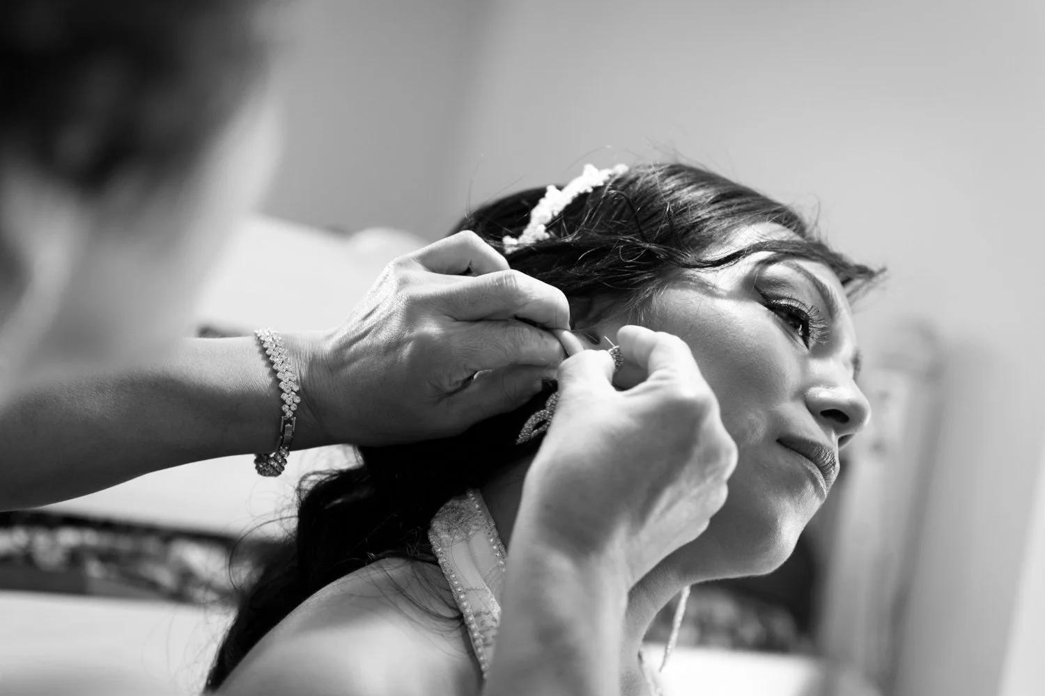 A woman getting her ear pierces by a professional with the woman smiling and looking away.