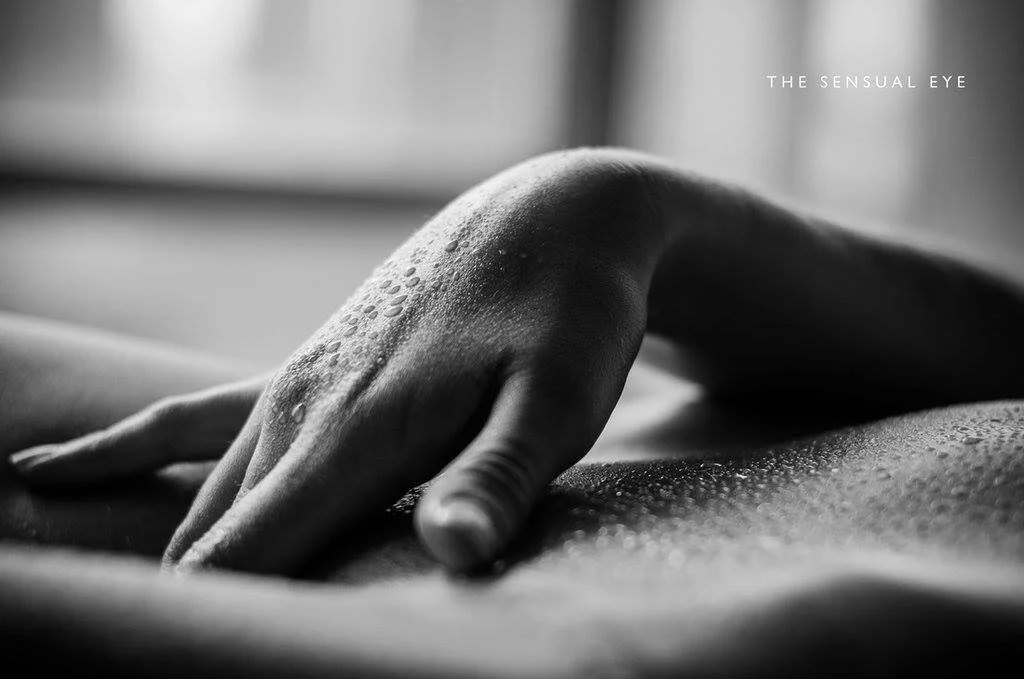 Close-up of a person's hand resting on a surface, with water droplets on the skin, in black and white.