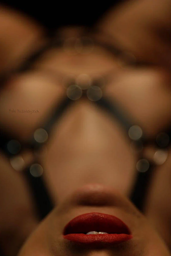 A close-up of a woman's face with red lipstick, viewed upside down with blurred background.