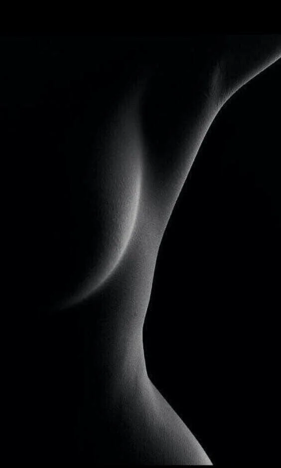 Close-up black and white photo of a woman's back and shoulder, highlighting the curve of her spine.