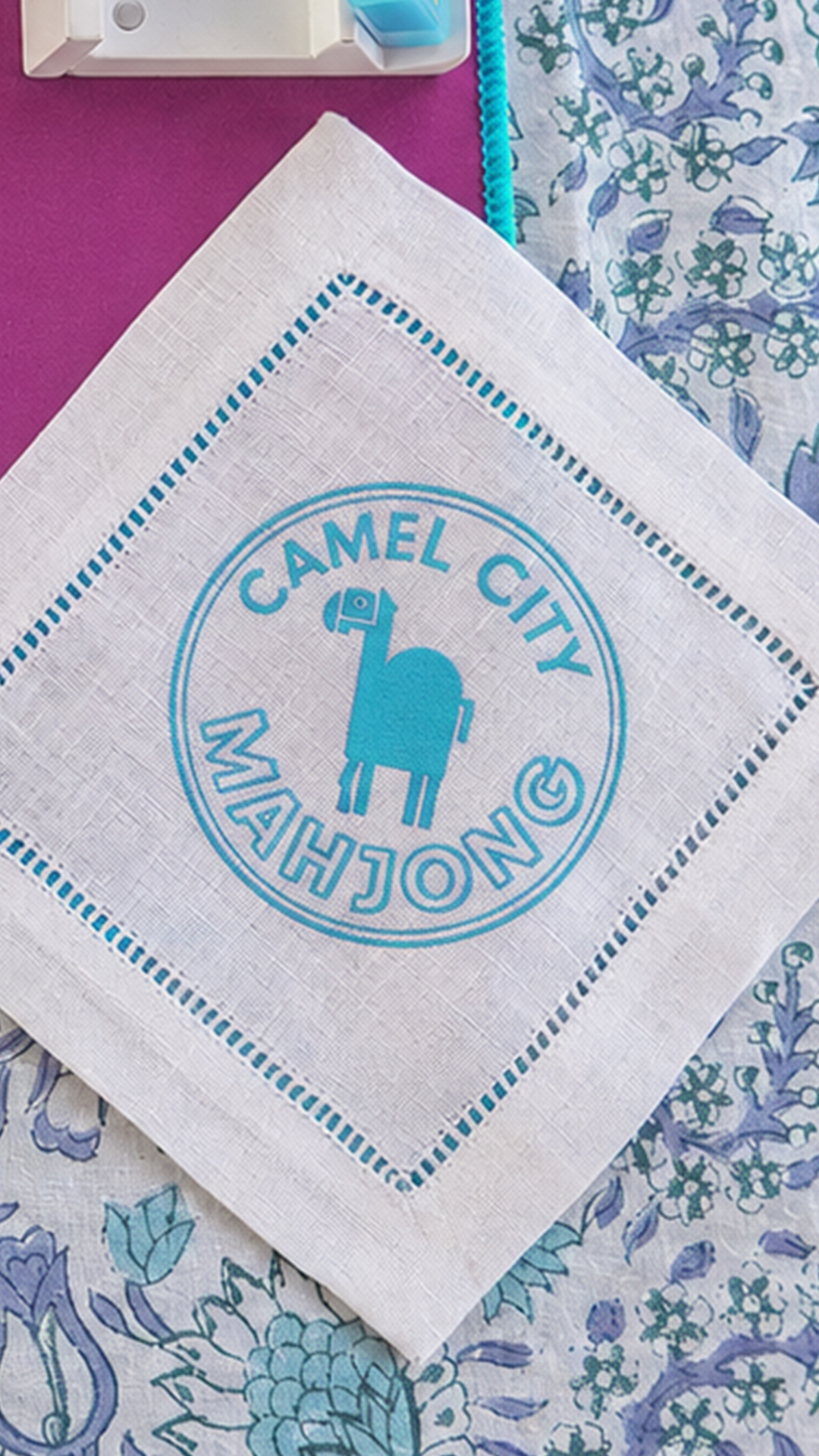 Camel City Mahjong logo embroidered on a white linen hemstitch cocktail napkin