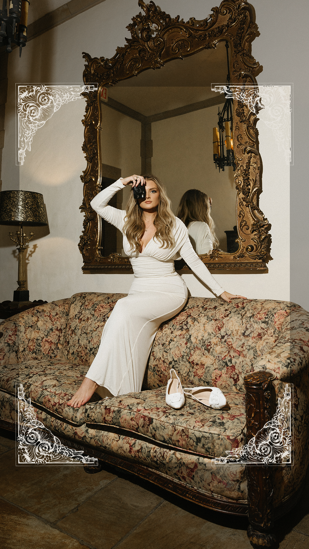 Behind-the-scenes brand photoshoot of luxury wedding photographer holding camera on vintage floral sofa