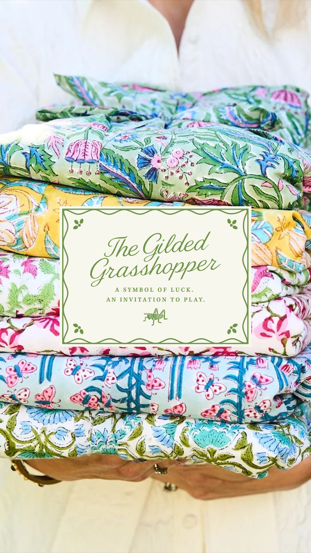 Stack of colorful block-print mahjong tablecloths with The Gilded Grasshopper branded label, a grandmillennial table linen brand