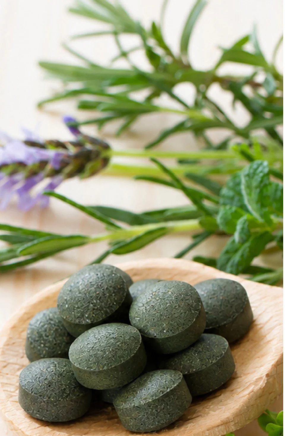Kapynatura dietary supplement tablets from Laboratorios Kapyderm on a wooden spoon with fresh herbs